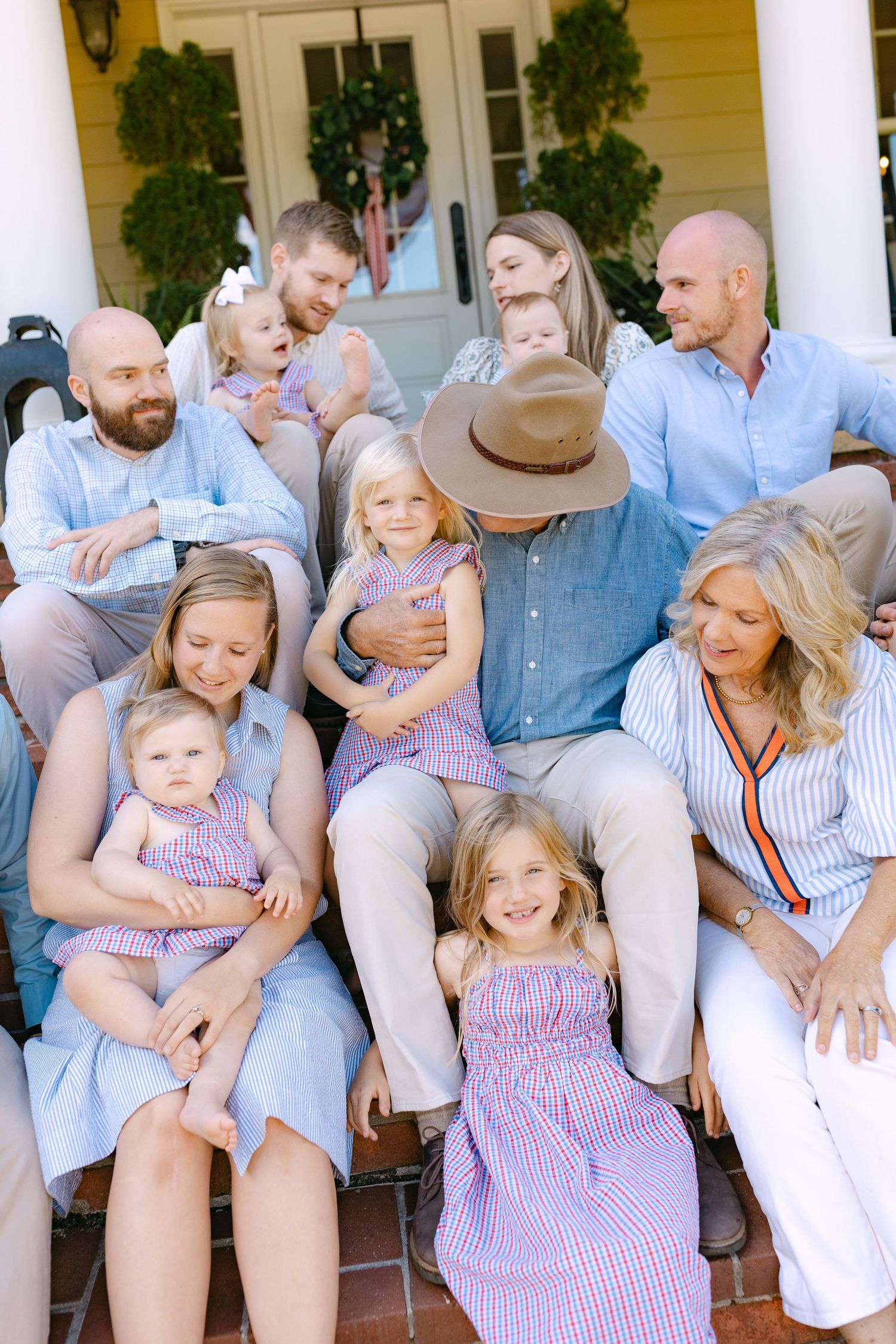 Large family portrait on porch steps wearing coordinated blue and white outfits with children and grandparents.
