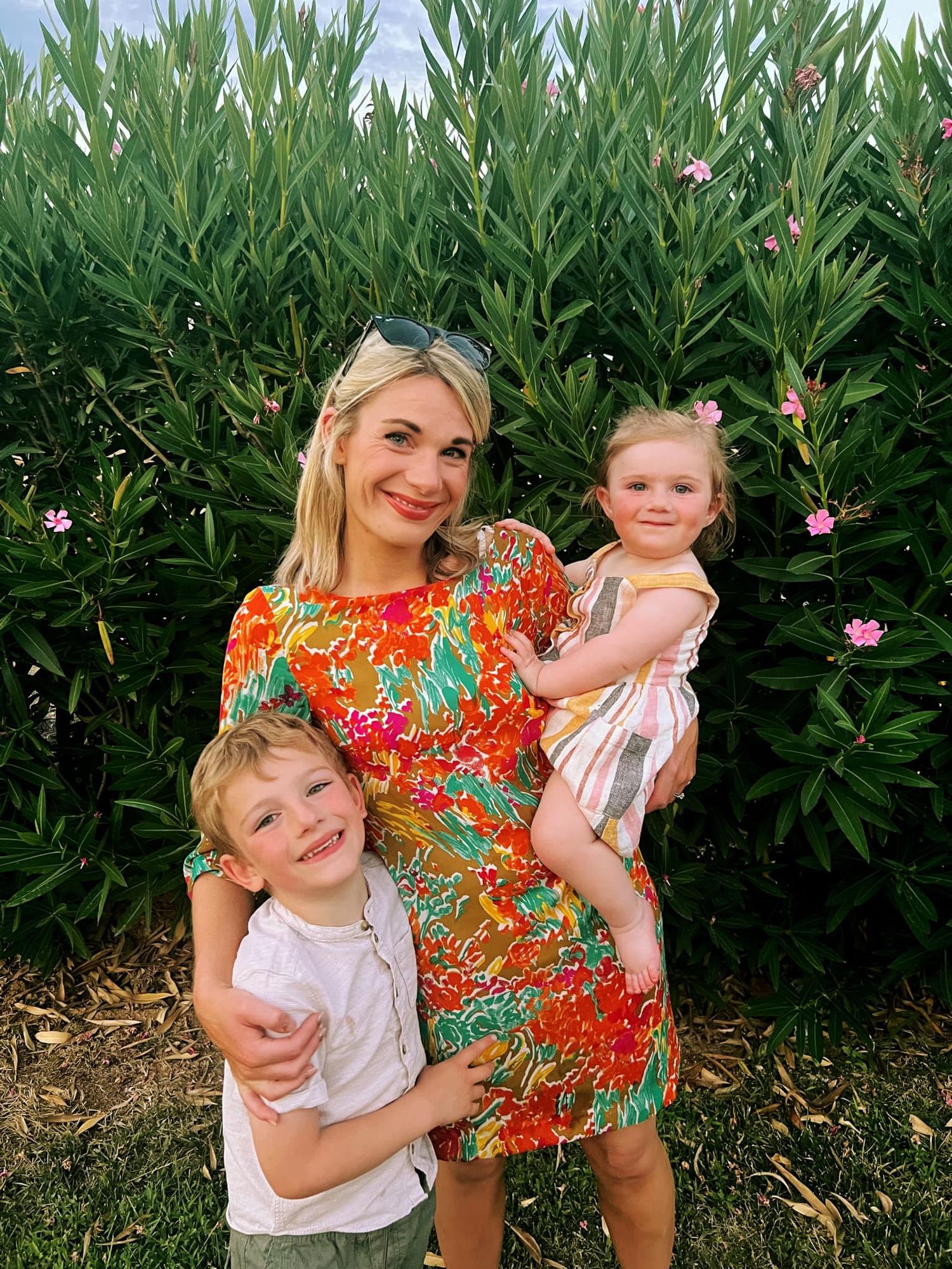 Summer portrait against flowering bush with vibrant floral dress and greenery.