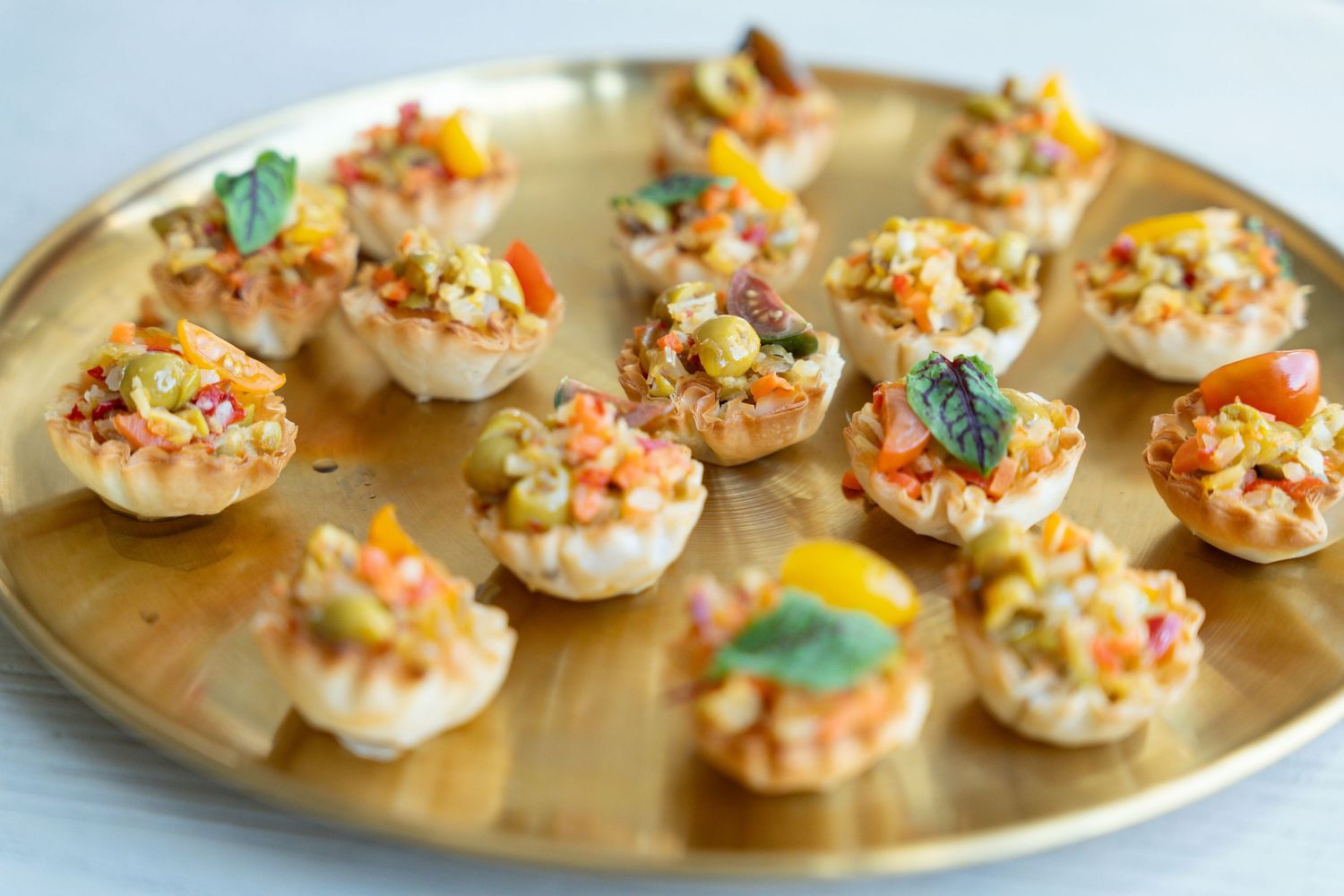 Mini phyllo pastry cups filled with savory shrimp salad and garnished with fresh herbs on a wooden serving platter.