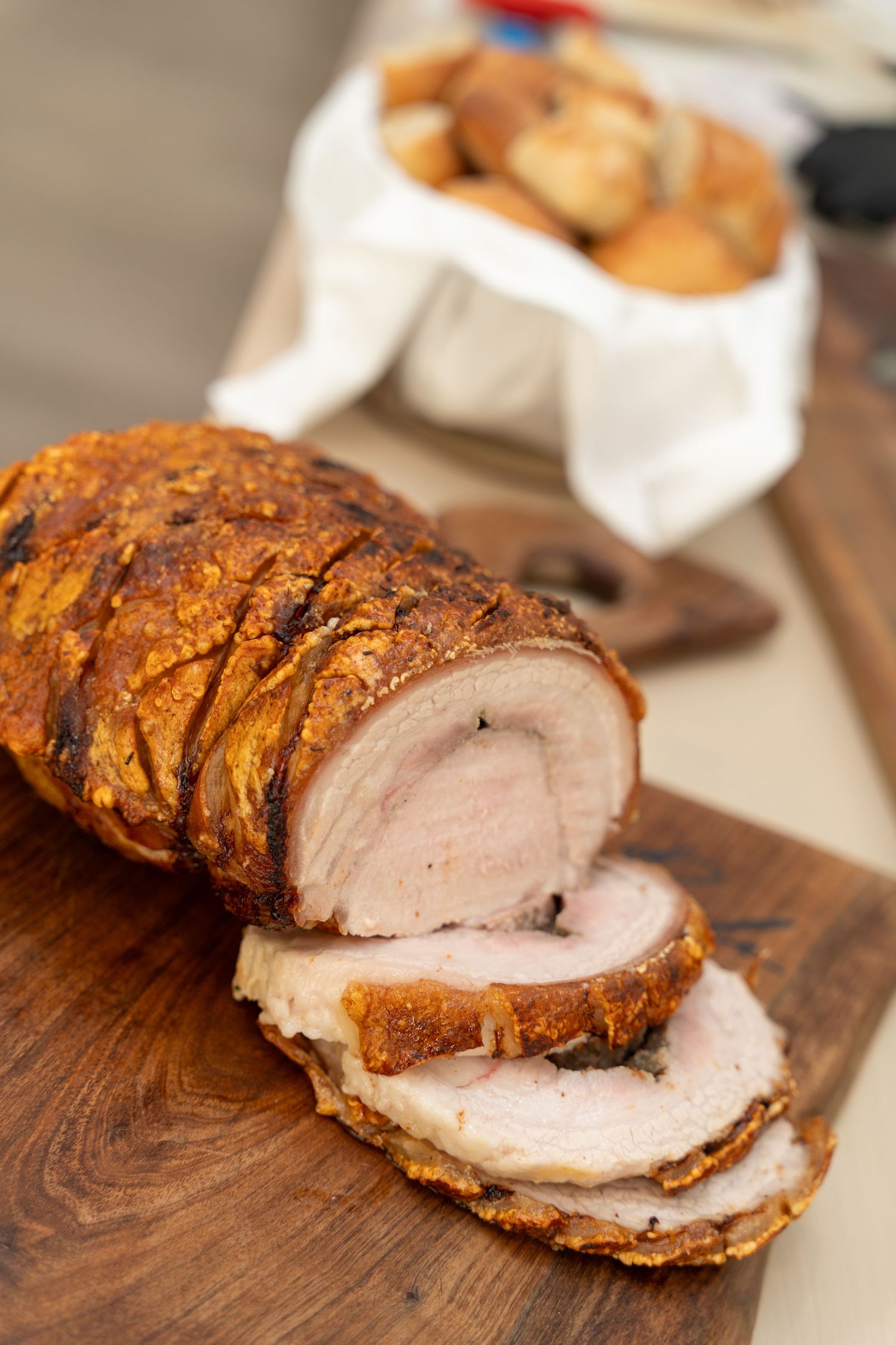 Sliced pork tenderloin with crispy brown exterior displayed on a wooden cutting board showing juicy pink center.
