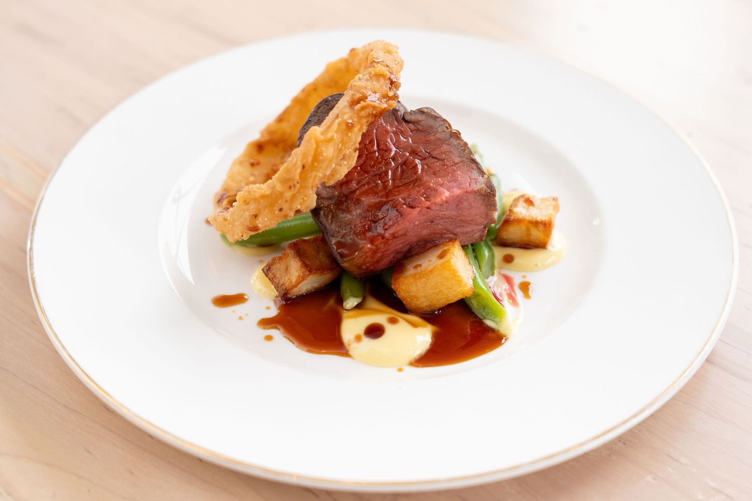 Elegant plated dish featuring seared meat and roasted potatoes garnished with fresh herbs on white plates.
