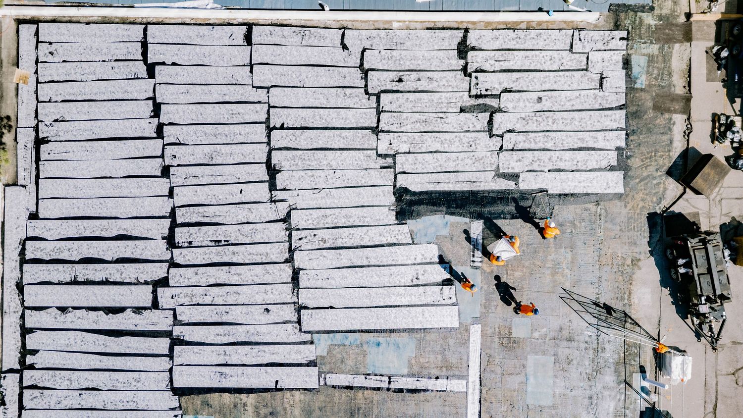 Aerial view of white industrial warehouse rooftops and buildings in an urban area during daytime.