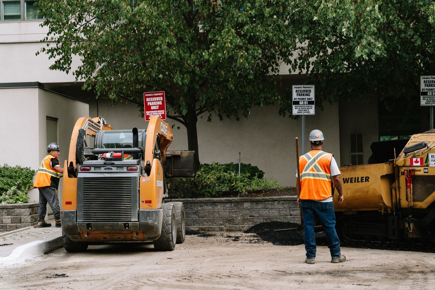 Workers operating construction equipment and machinery in a residential development area.