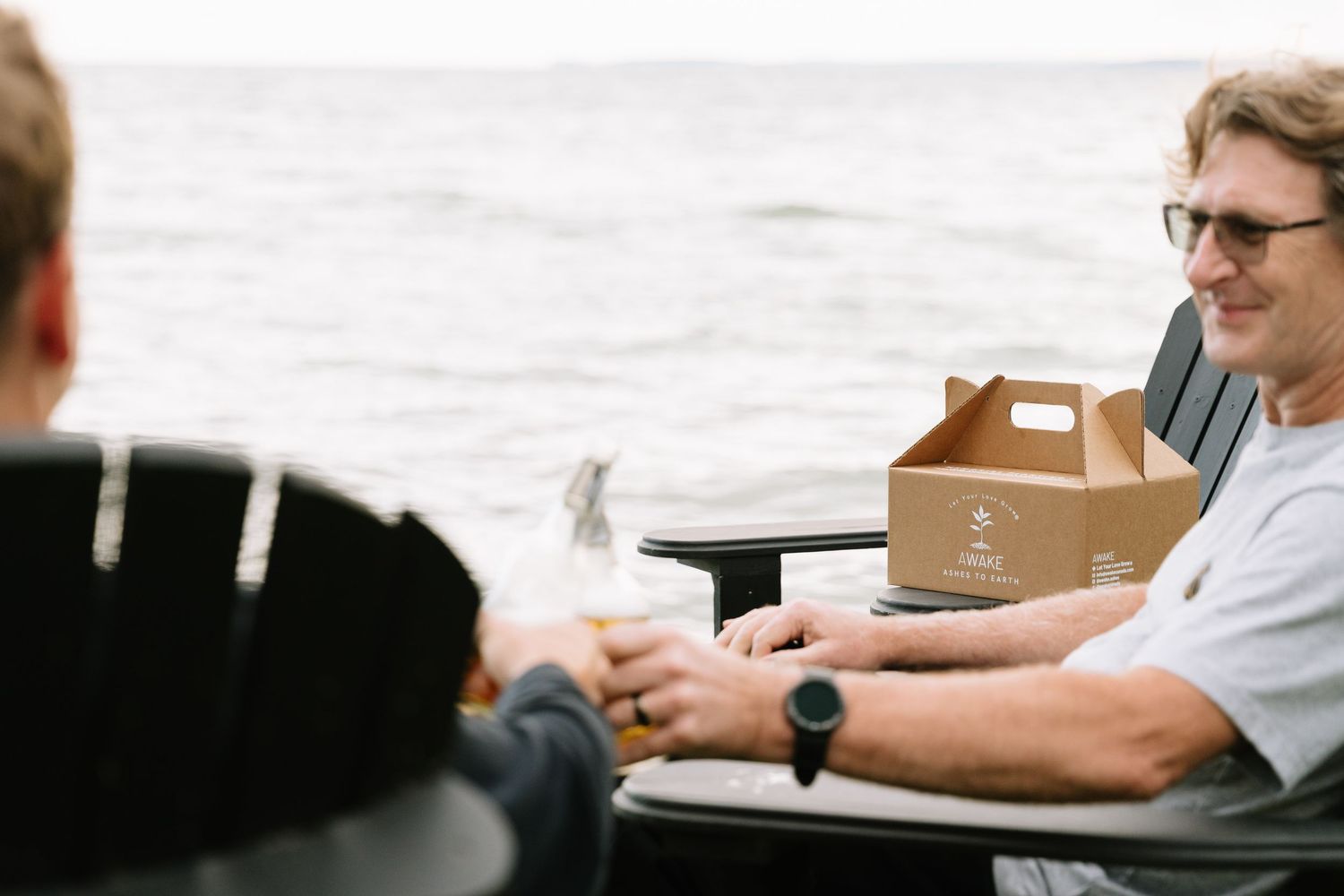 People sitting at a table with brown cardboard boxes and packaging materials in a casual business setting.