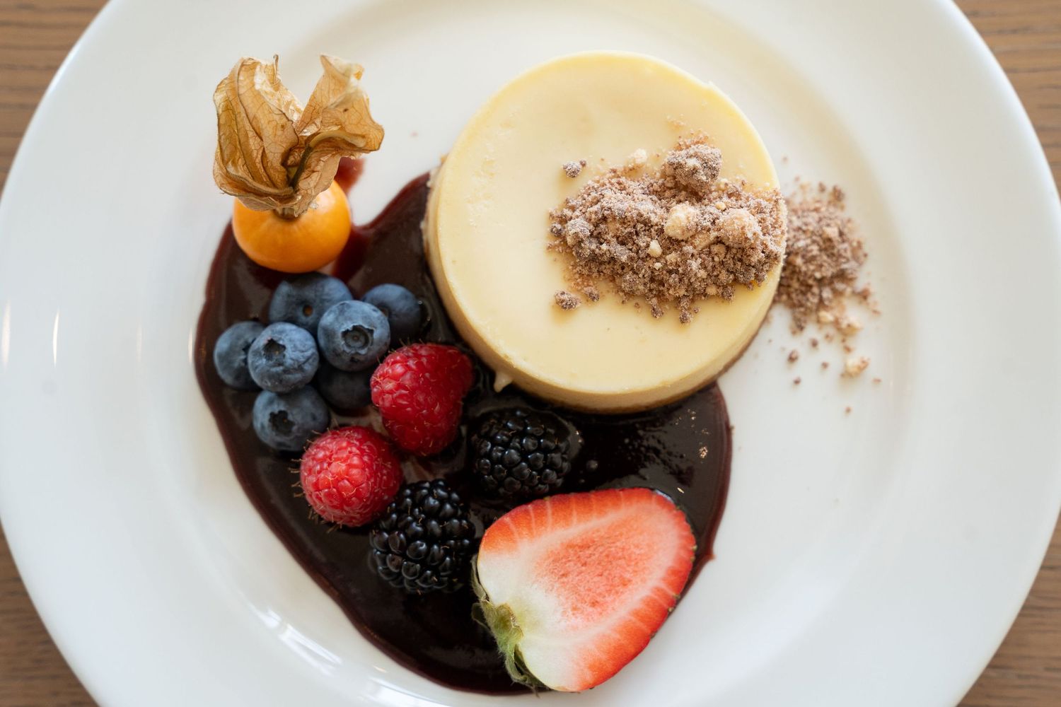 Fresh mixed berries and sliced peaches arranged on white plates with dark sauce and garnish.