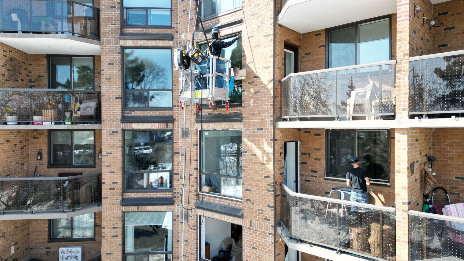 Modern apartment building interior with exposed brick columns and glass walls creating an open, industrial-chic space.
