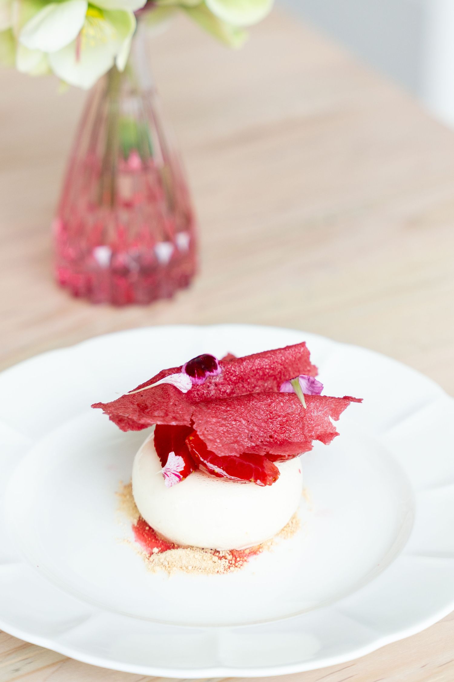 Elegant dessert with red garnish and white cream on delicate china plate.
