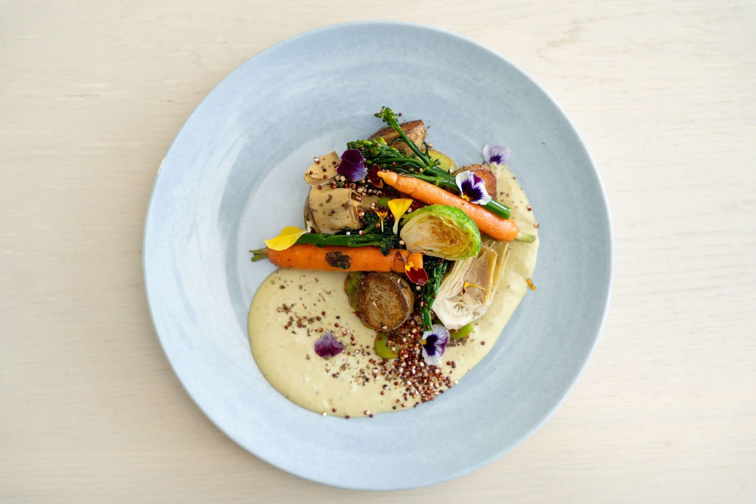 Elegant plated dish featuring seared fish with delicate garnishes on a pale blue ceramic plate.