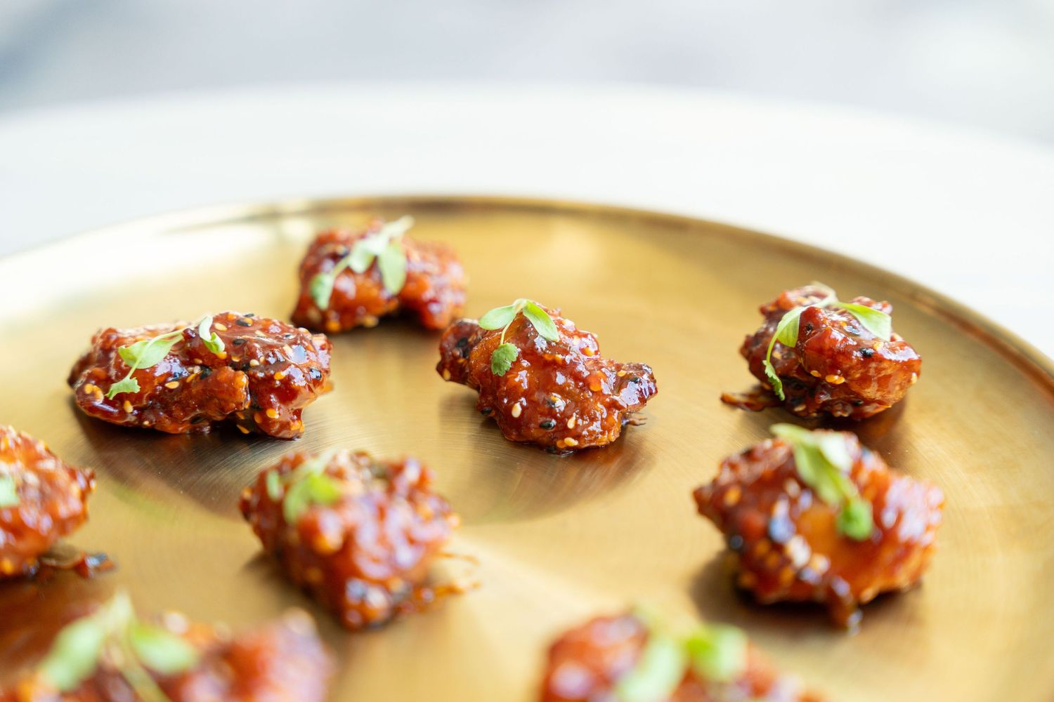 Small round appetizers garnished with red sauce arranged on a gold serving platter.