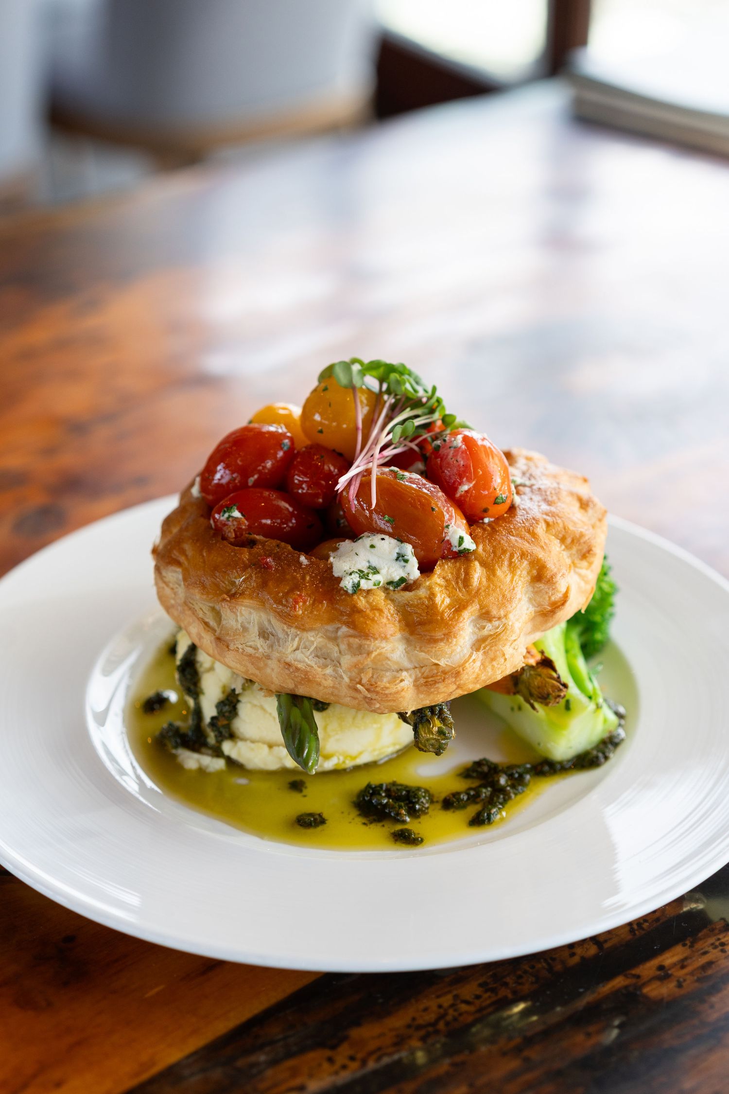 Elegant plated appetizers featuring puff pastry topped with fresh herbs and colorful garnishes on white plates.