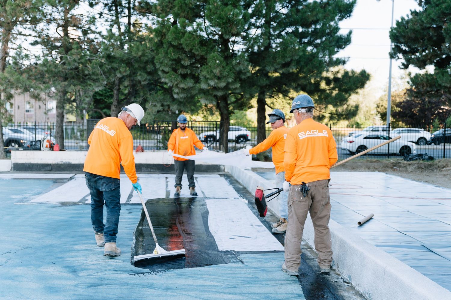 Skateboarders in bright orange shirts practice tricks on concrete ledges in an urban setting.