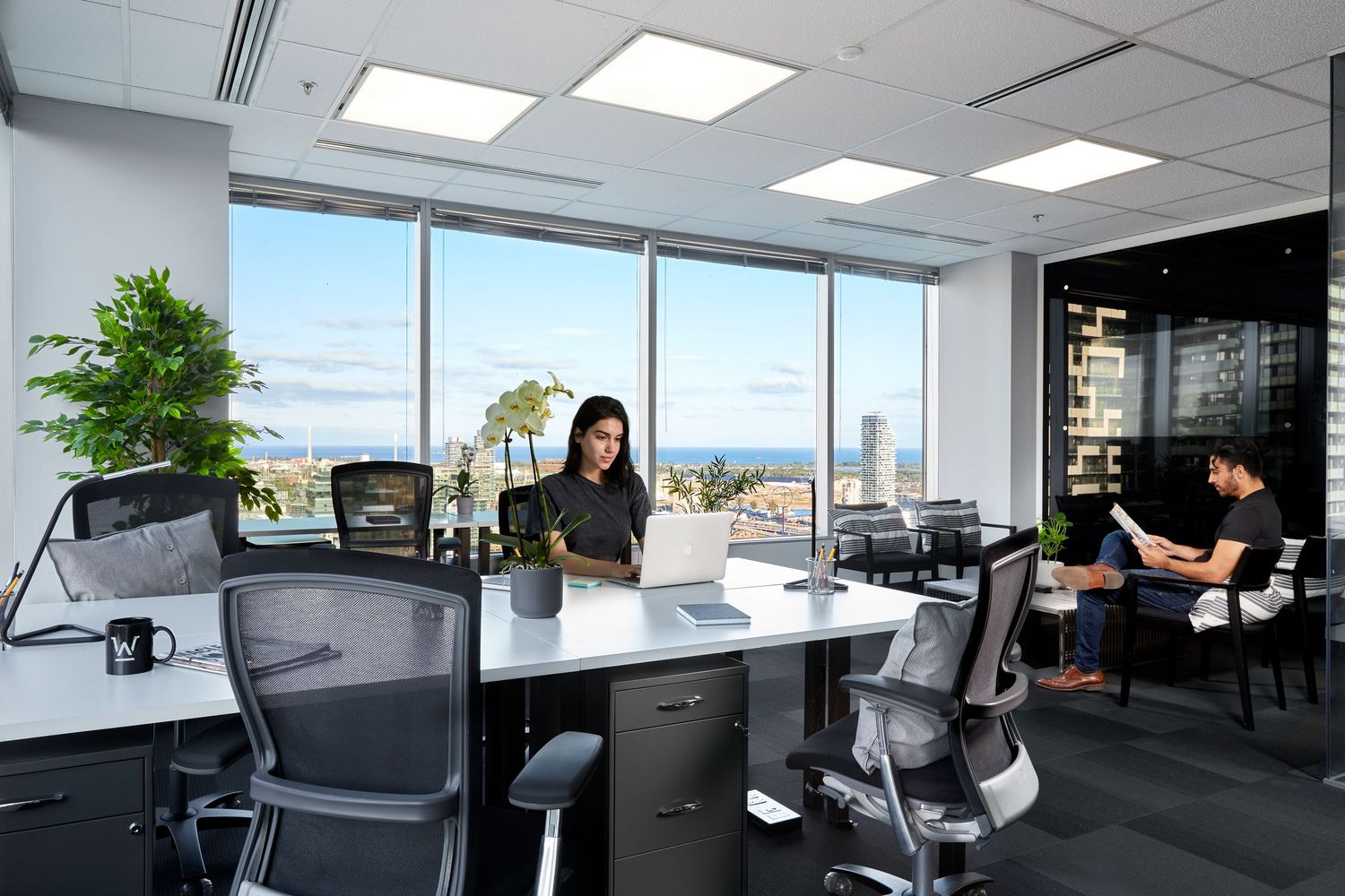 Modern office space with glass walls, workstations, and natural lighting showcases a contemporary corporate environment.