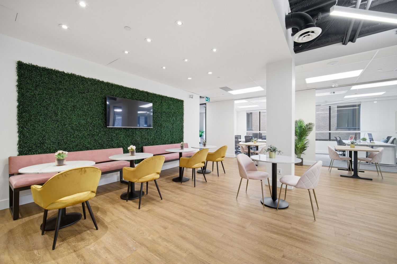 Modern office interior with yellow chairs, white walls, and a green accent wall featuring open workspace design.
