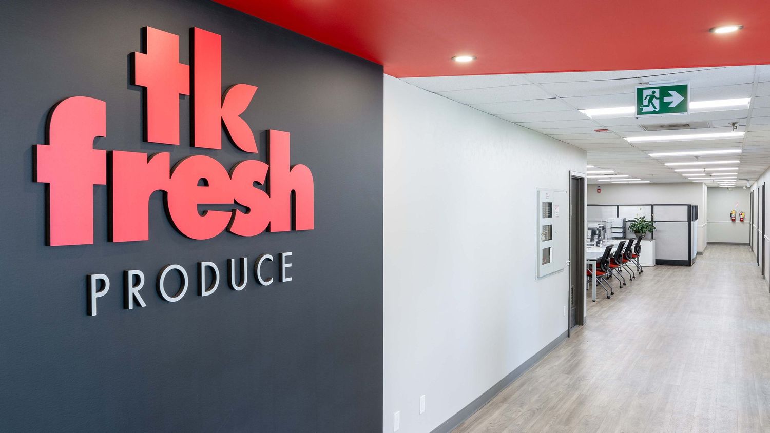 Modern office hallway with pink neon signage and white walls illuminated by recessed lighting.