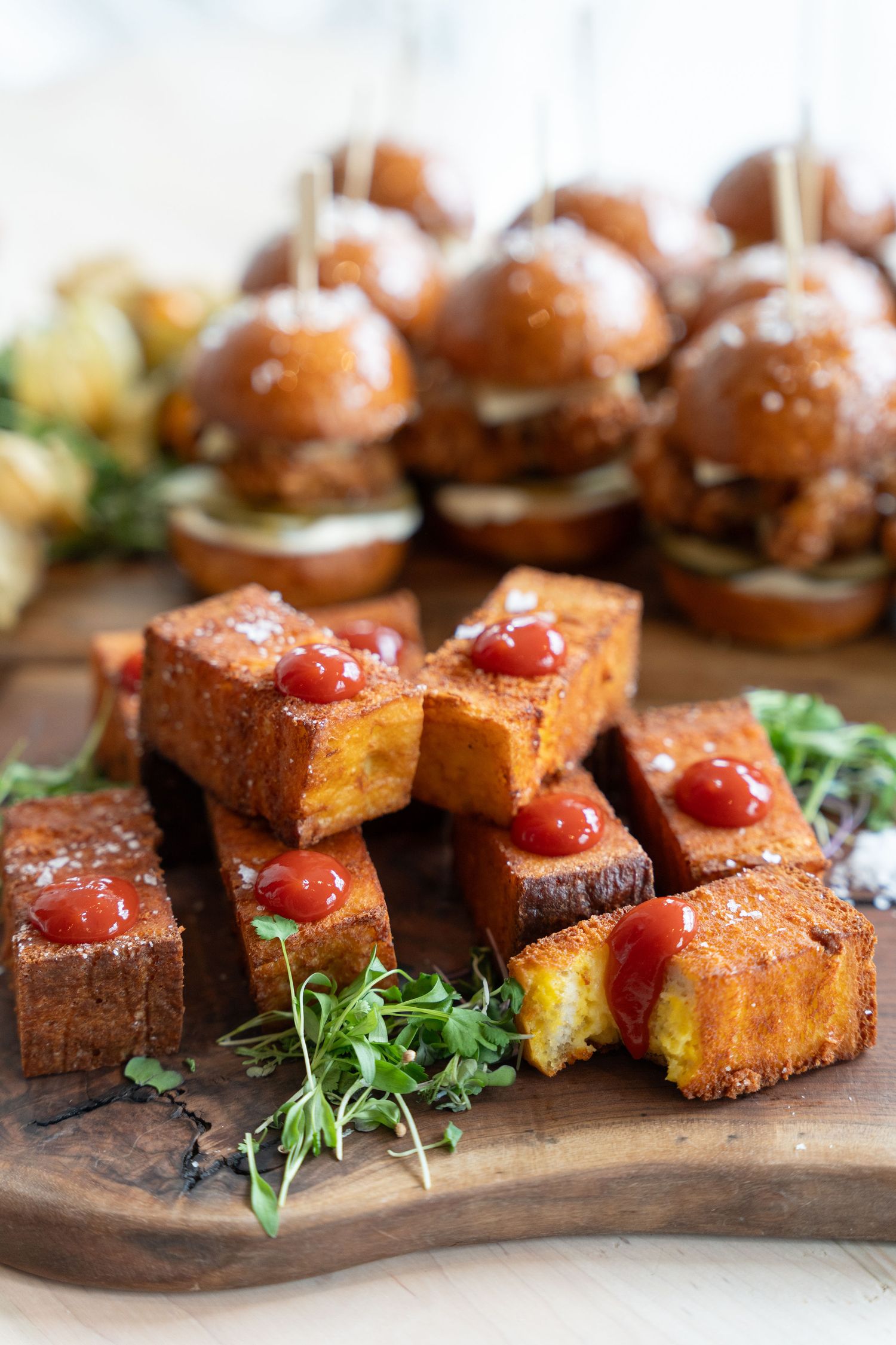 Golden-brown polenta squares topped with roasted cherry tomatoes and fresh herbs on a rustic wooden board.