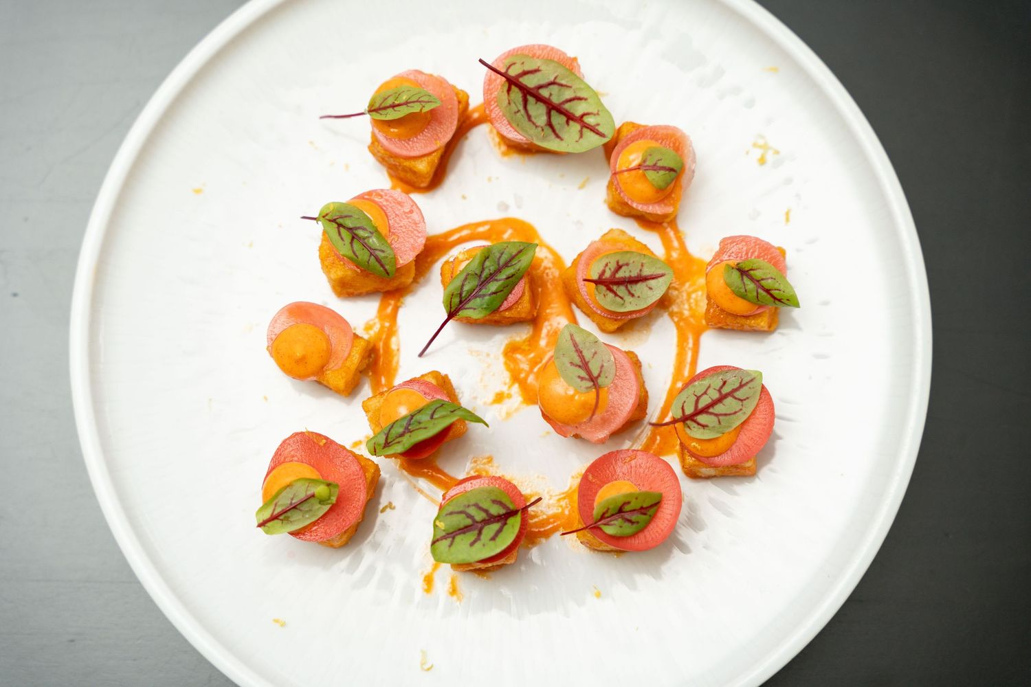 Artfully plated smoked salmon bites garnished with fresh herbs on a white plate.