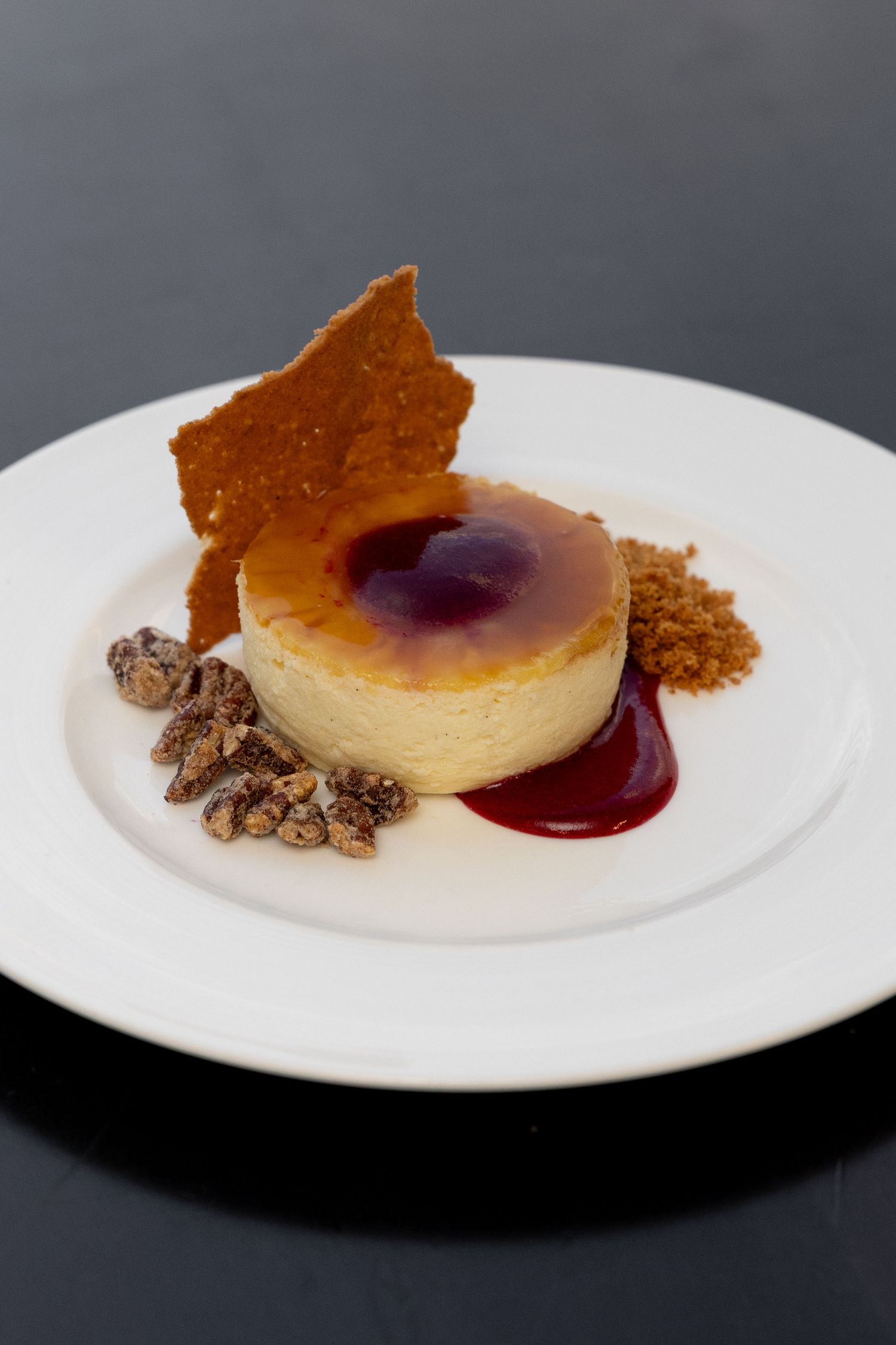 A sequence of plated desserts showing a crème brûlée with berry sauce and crumble garnish on white plates.