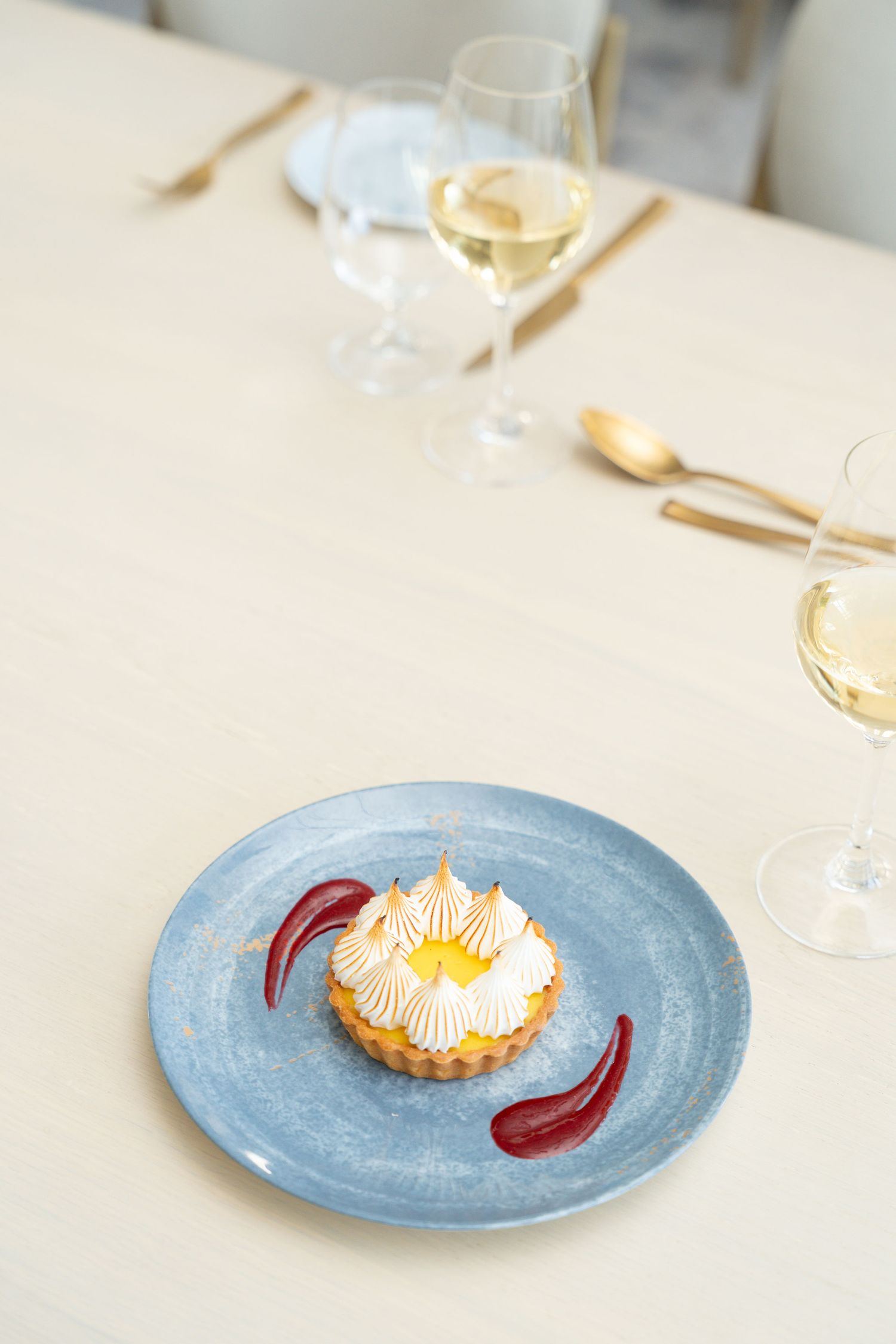 A sequence of plated desserts with meringue and red sauce on light blue plates showing progressive consumption.