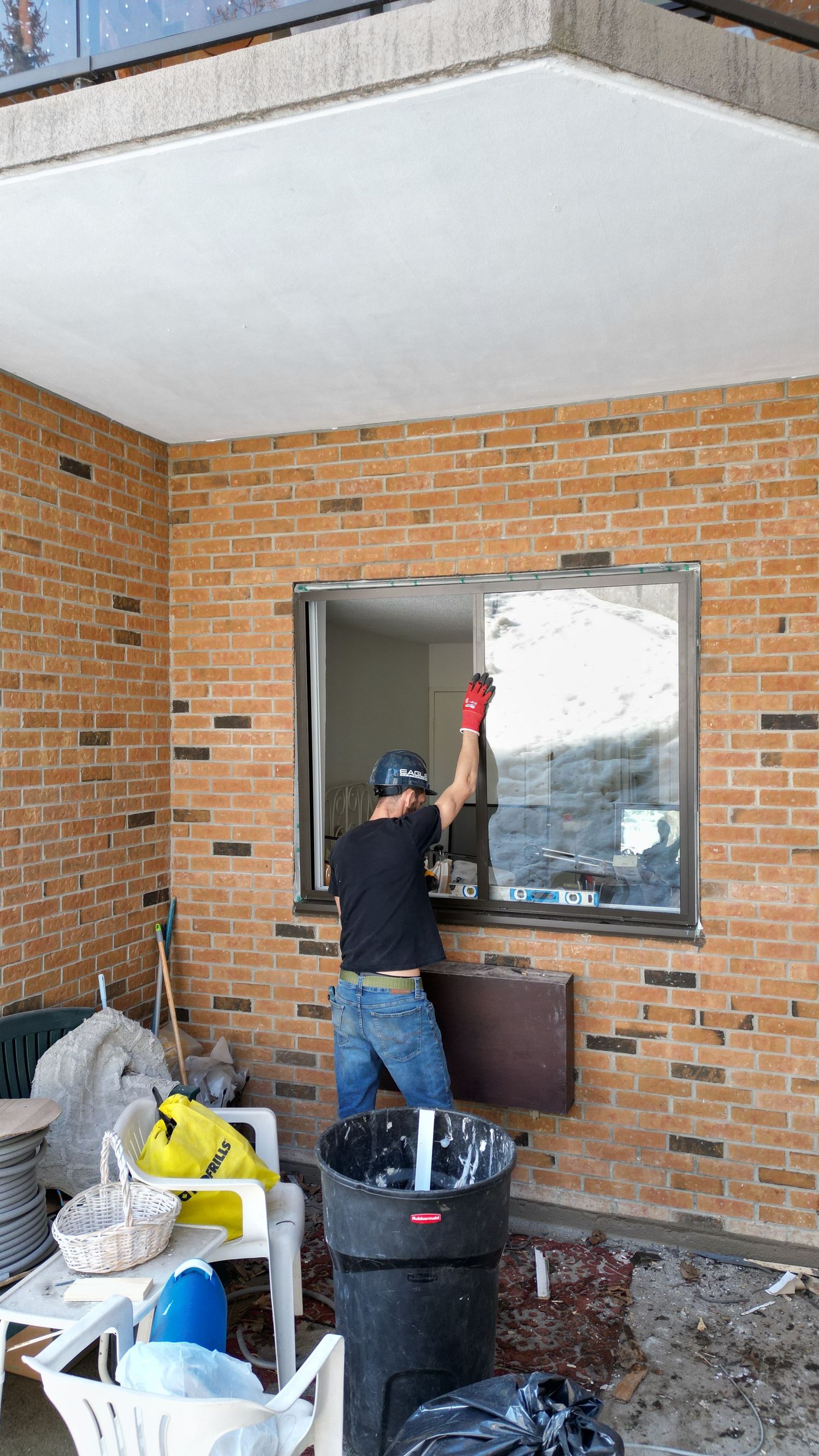 Maintenance work being performed on brick building windows with equipment and supplies visible.