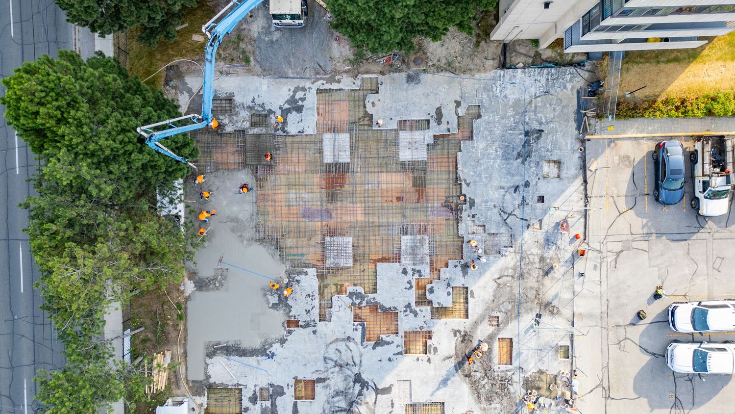 Aerial view of a residential neighborhood with swimming pools and parked cars on a sunny day.