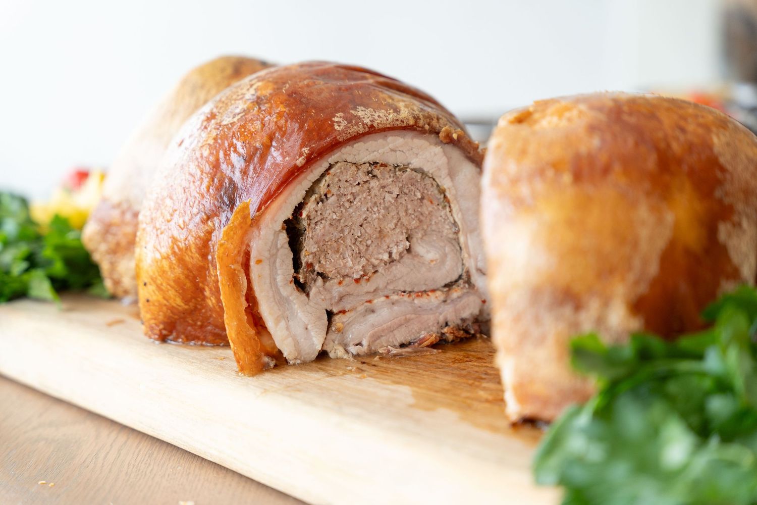 Sliced pork tenderloin wrapped in golden-brown pastry displayed on a white surface with fresh herbs.