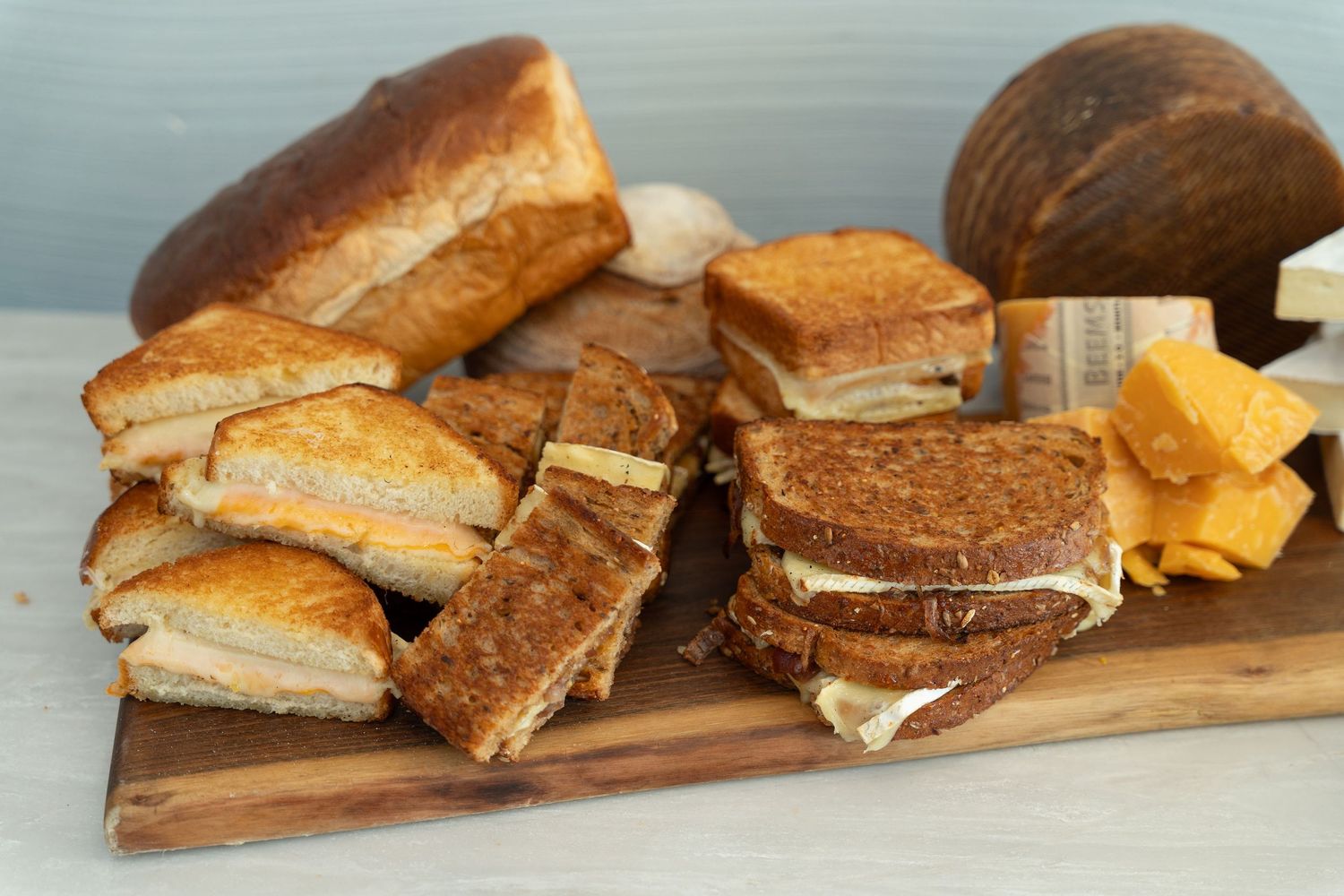 Assorted artisanal sandwiches displayed on a rustic wooden serving board.