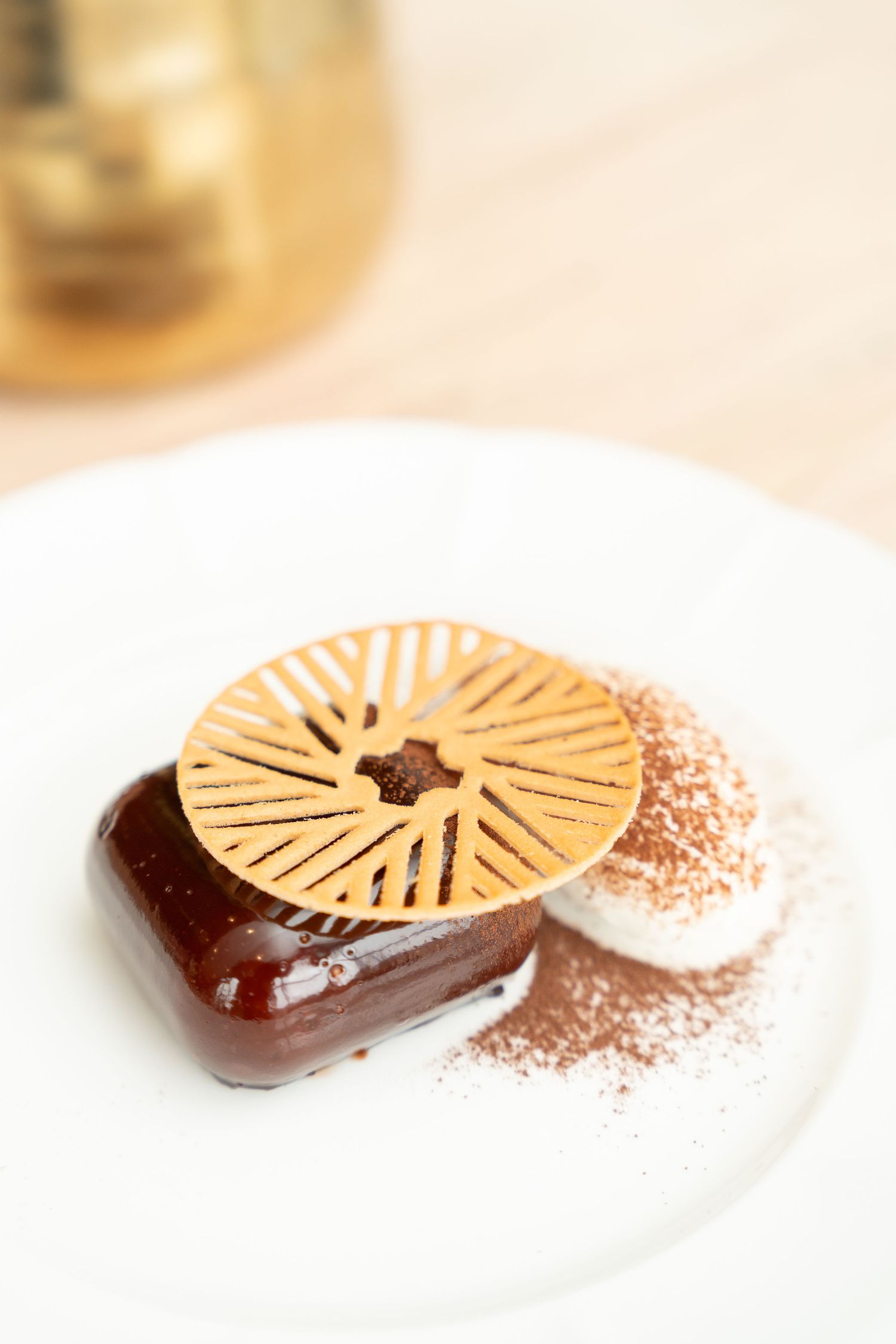 Decorative chocolate desserts with geometric patterns and cocoa powder dusting on white plates.