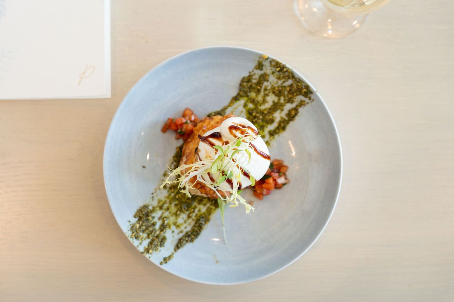 A plate of sushi rolls with green matcha coating and white cream sauce drizzled on top.