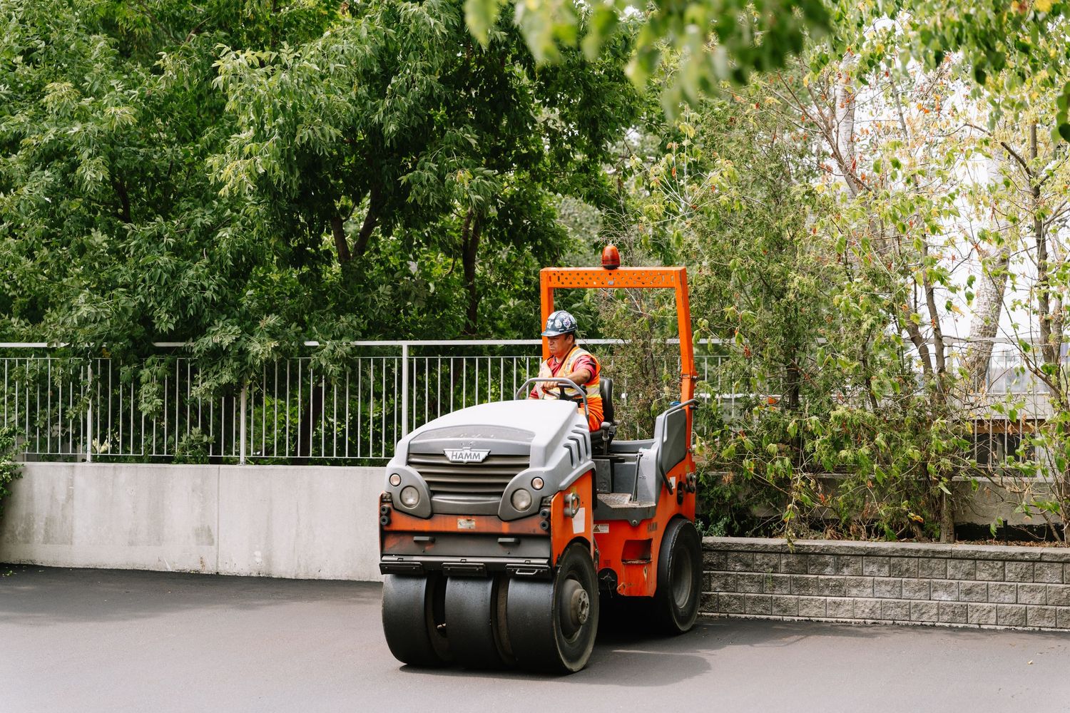 Heavy construction vehicles and equipment lined up along a residential building during roadwork.