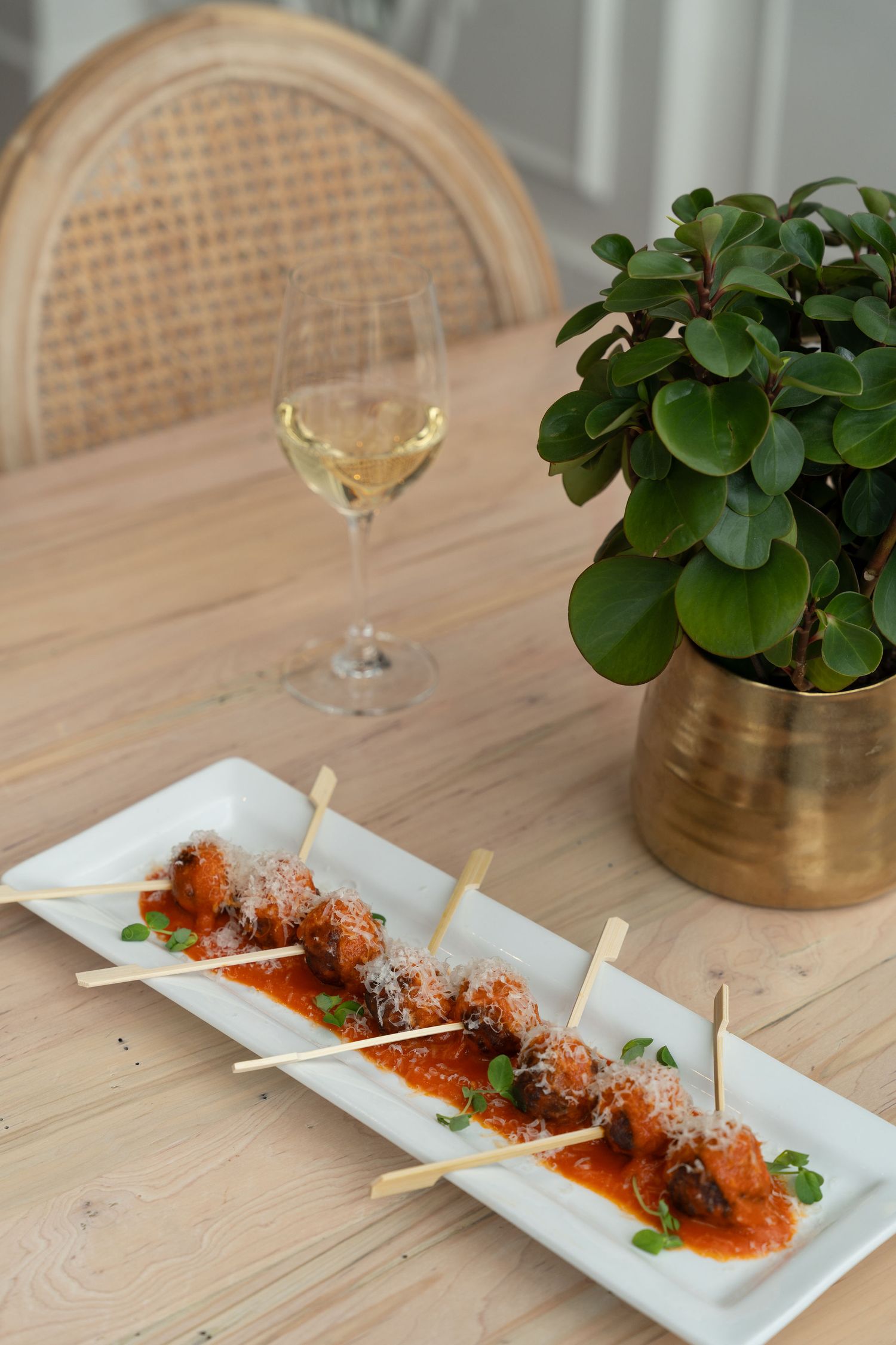White rectangular plate with grilled skewered meat in spicy red sauce garnished with fresh herbs.