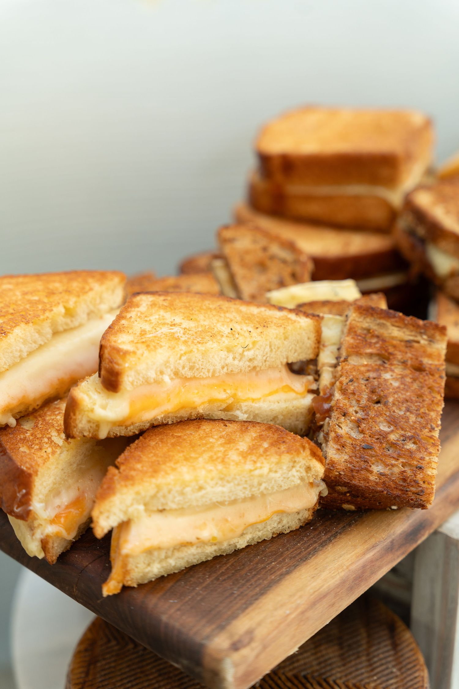 Grilled cheese sandwiches with golden brown crusts displayed on a wooden serving board.
