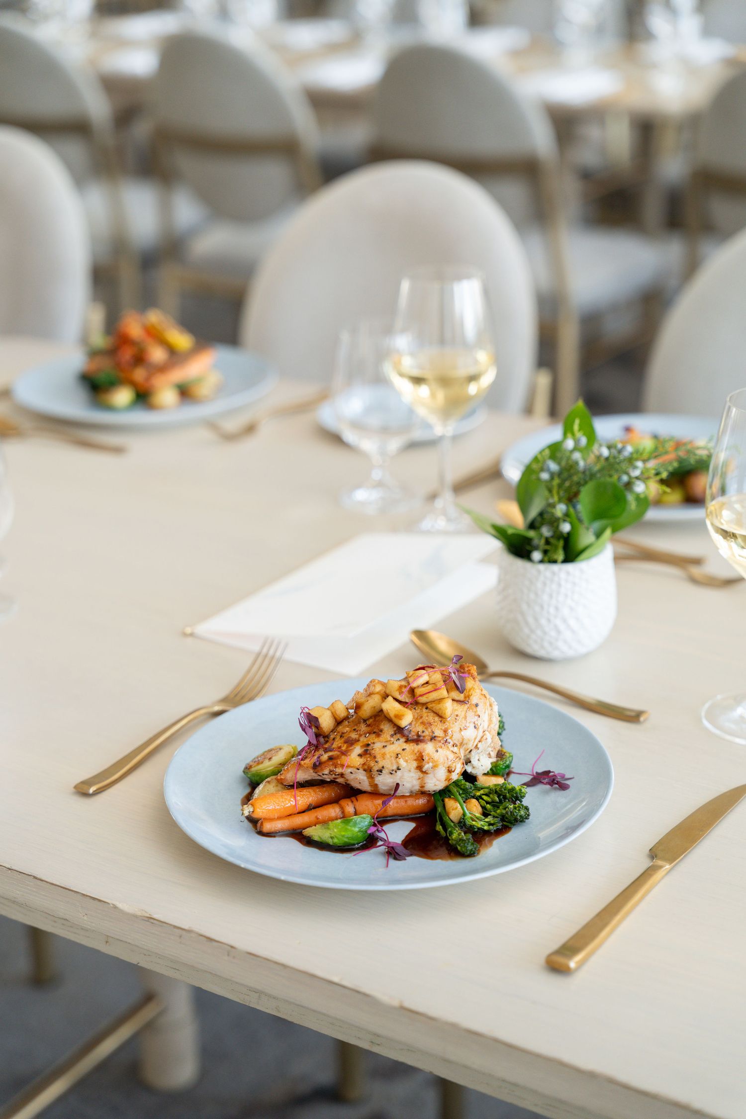 Elegantly plated salmon dish with vegetables served on white plates in an upscale restaurant setting.