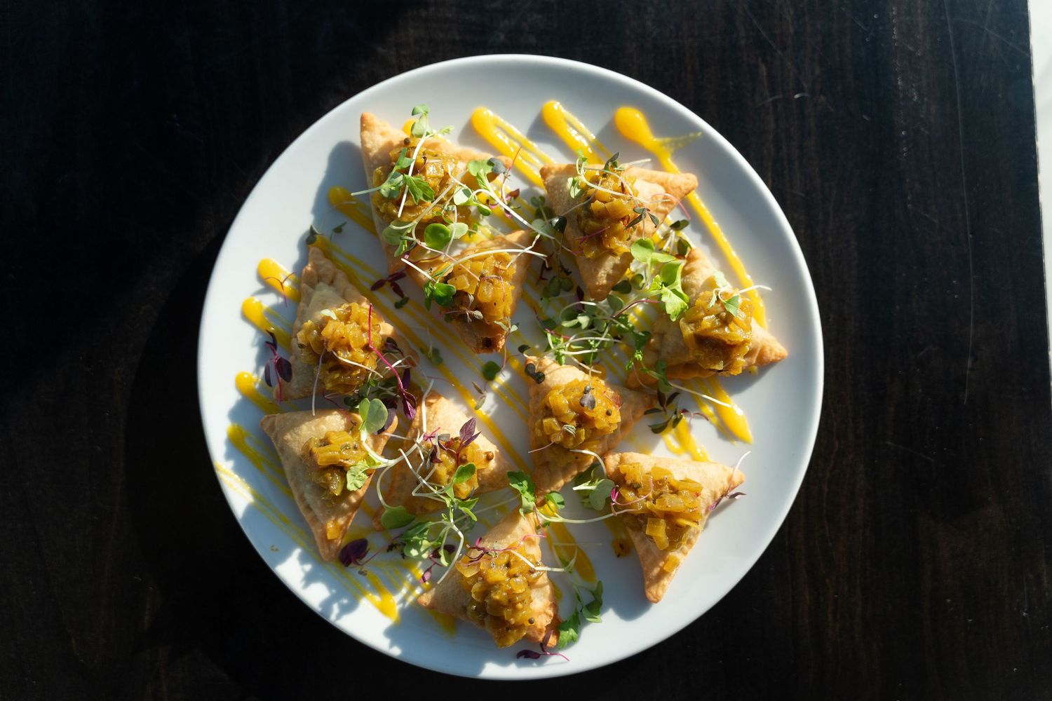 Yellow pasta squares topped with herbs and spices arranged on a white plate.