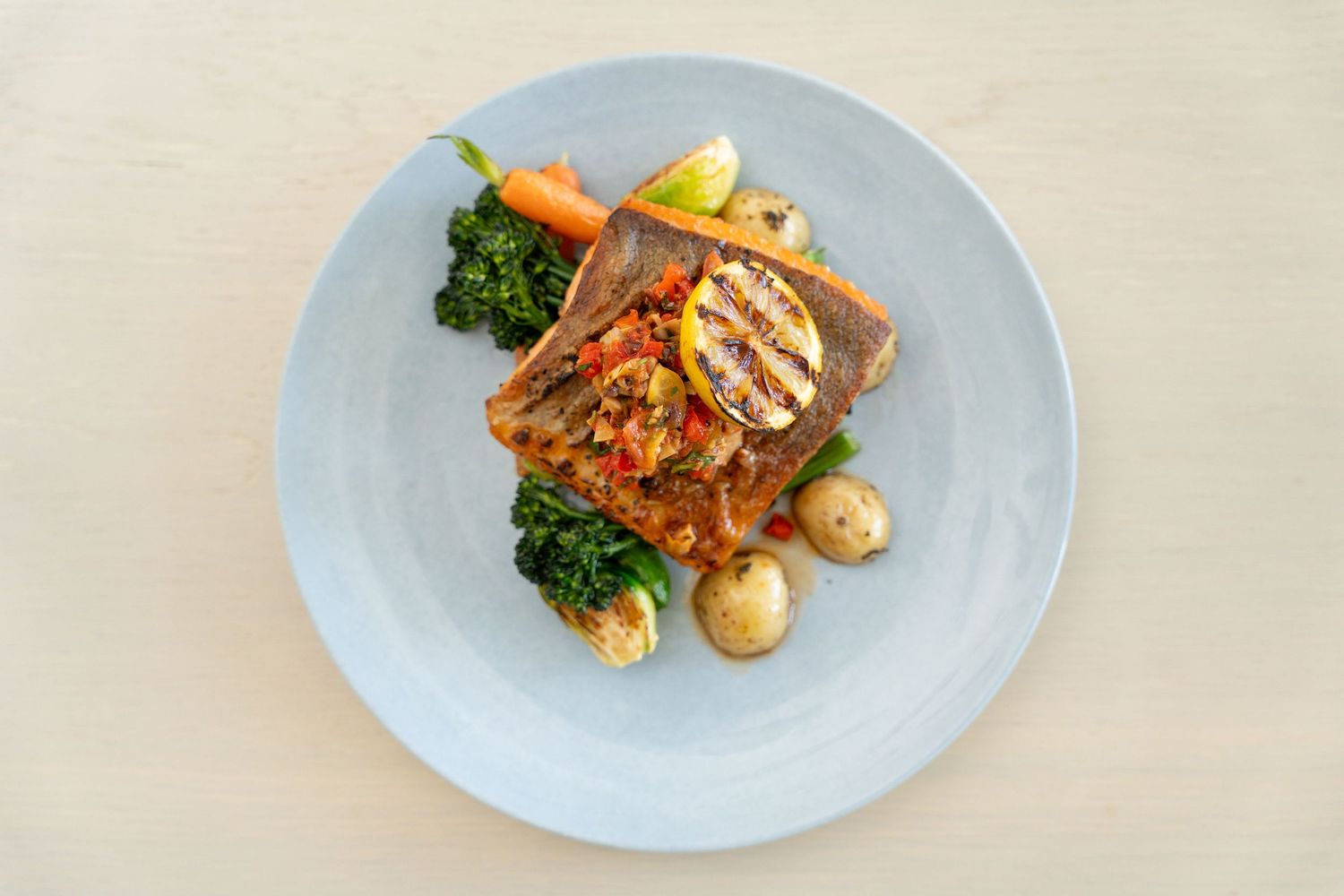 A series of elegant plated dishes with garnishes served on white plates against a light background.