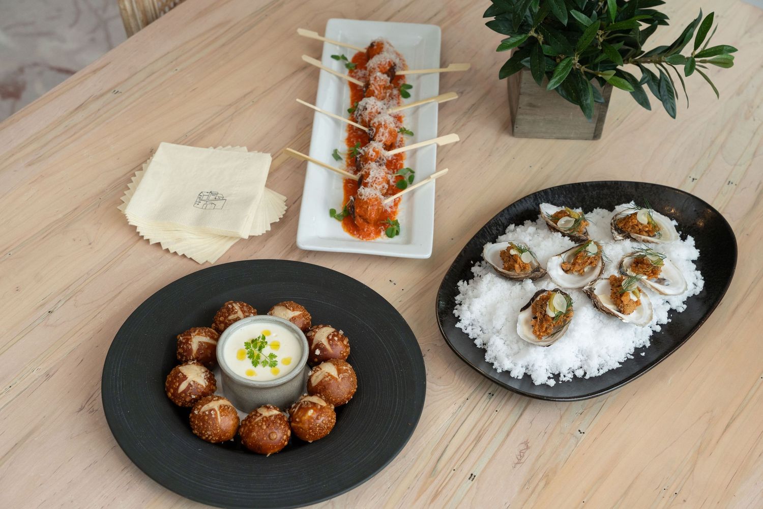 Elegant appetizer spread featuring small plates of hors d'oeuvres on a light wooden table setting.