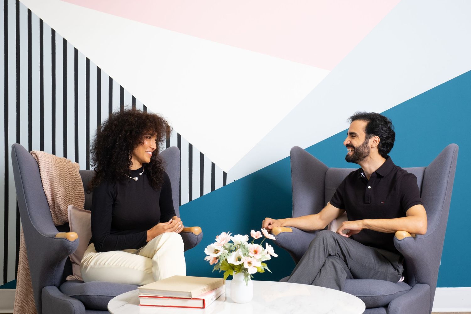 Professional meeting area with upholstered chairs and geometric wall design in contemporary office setting.