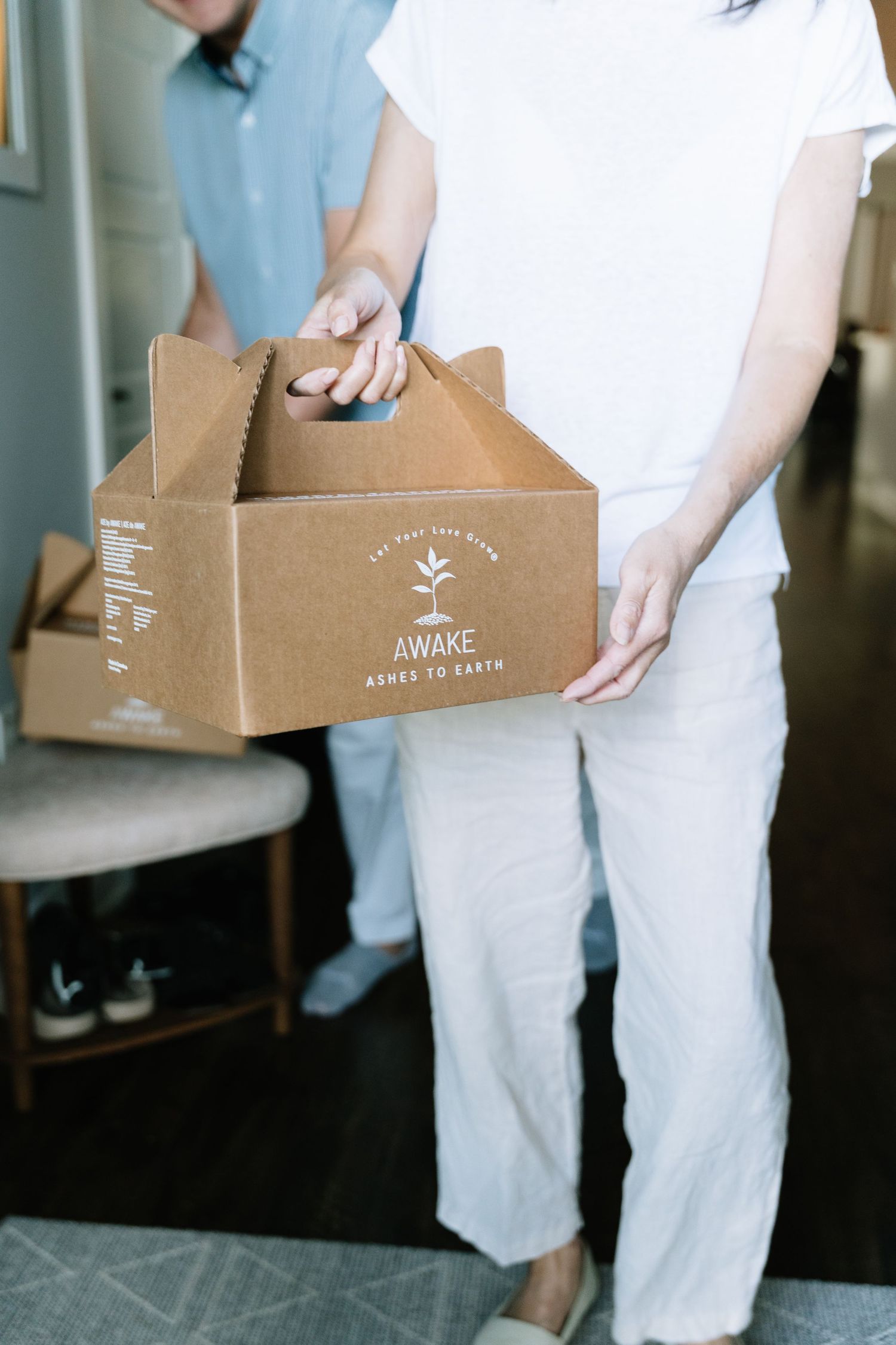 Hands holding brown cardboard boxes with 'Awake' branding shown in a sequence of four similar shots.