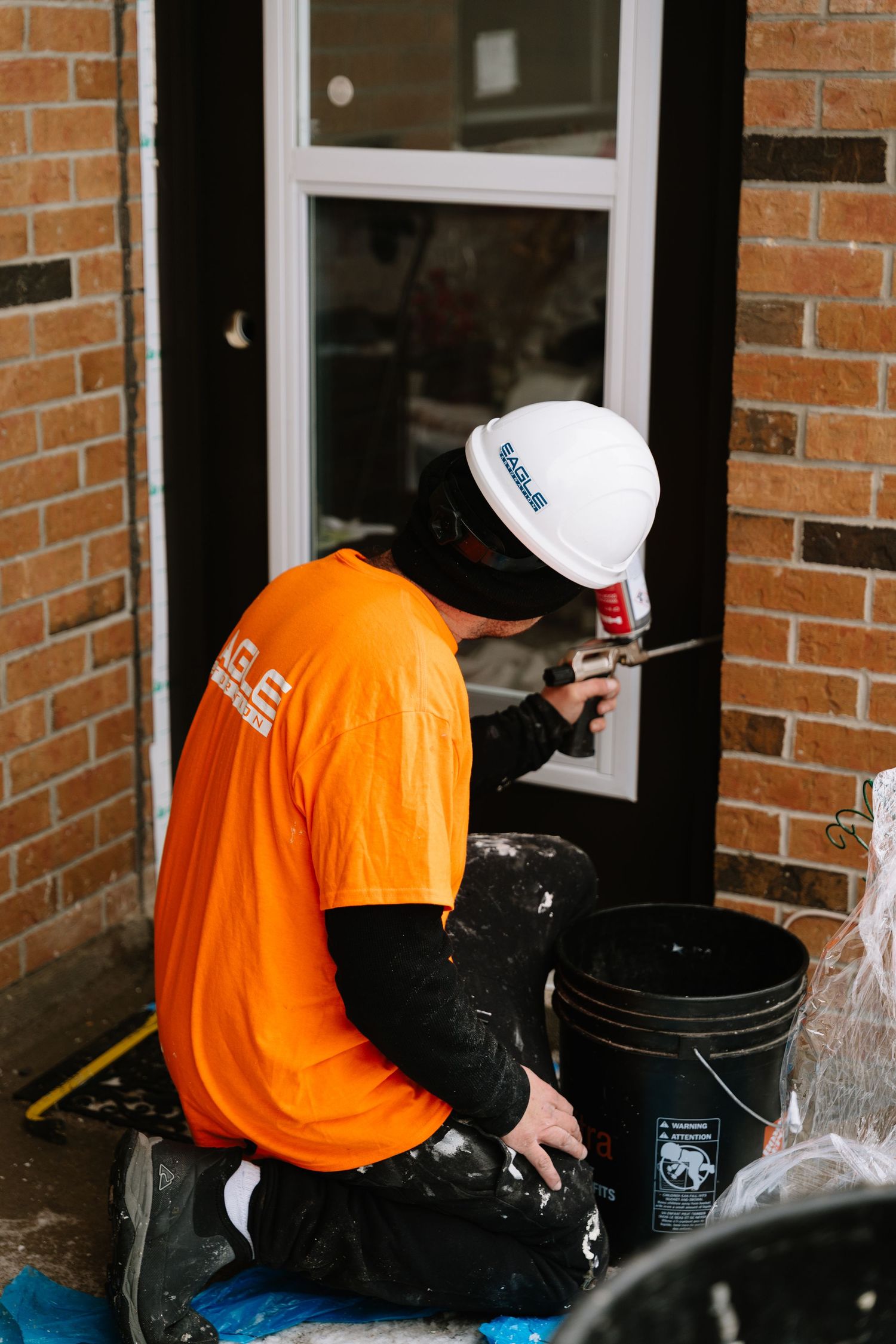 Maintenance workers in safety gear clean windows while standing on stepladders.