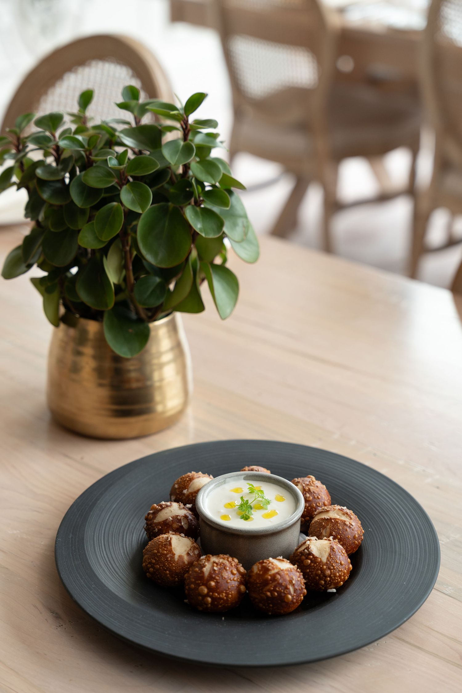 A series of four photos showing falafel served on dark plates with yogurt sauce and decorative potted plants.