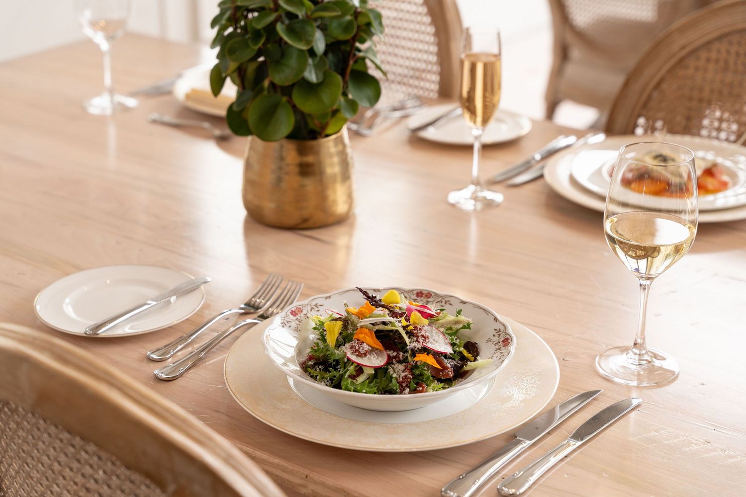 Elegant table setting with wine glasses and white plates in a restaurant's warm lighting atmosphere.