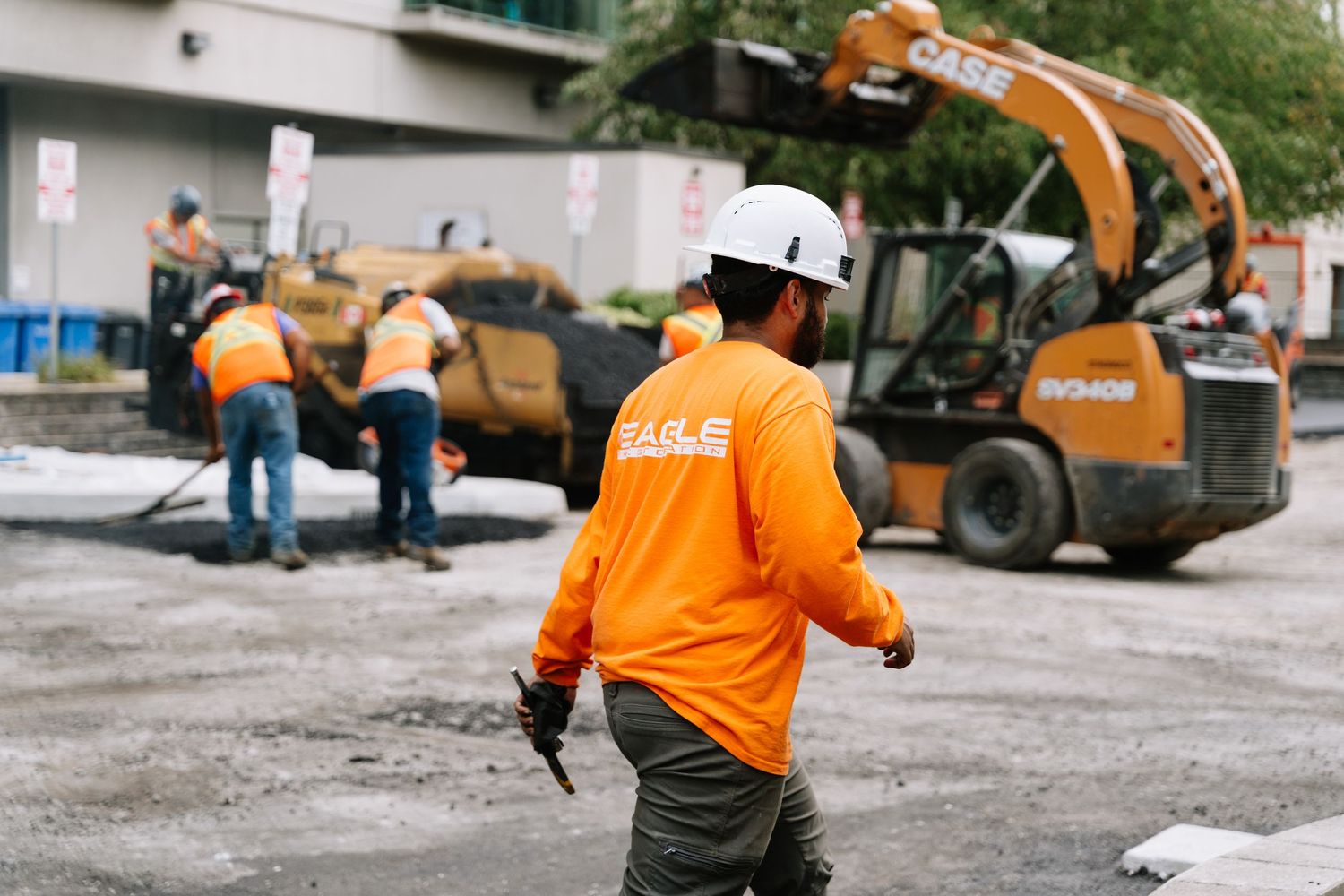 Construction crew in safety gear working with heavy equipment on a residential site.