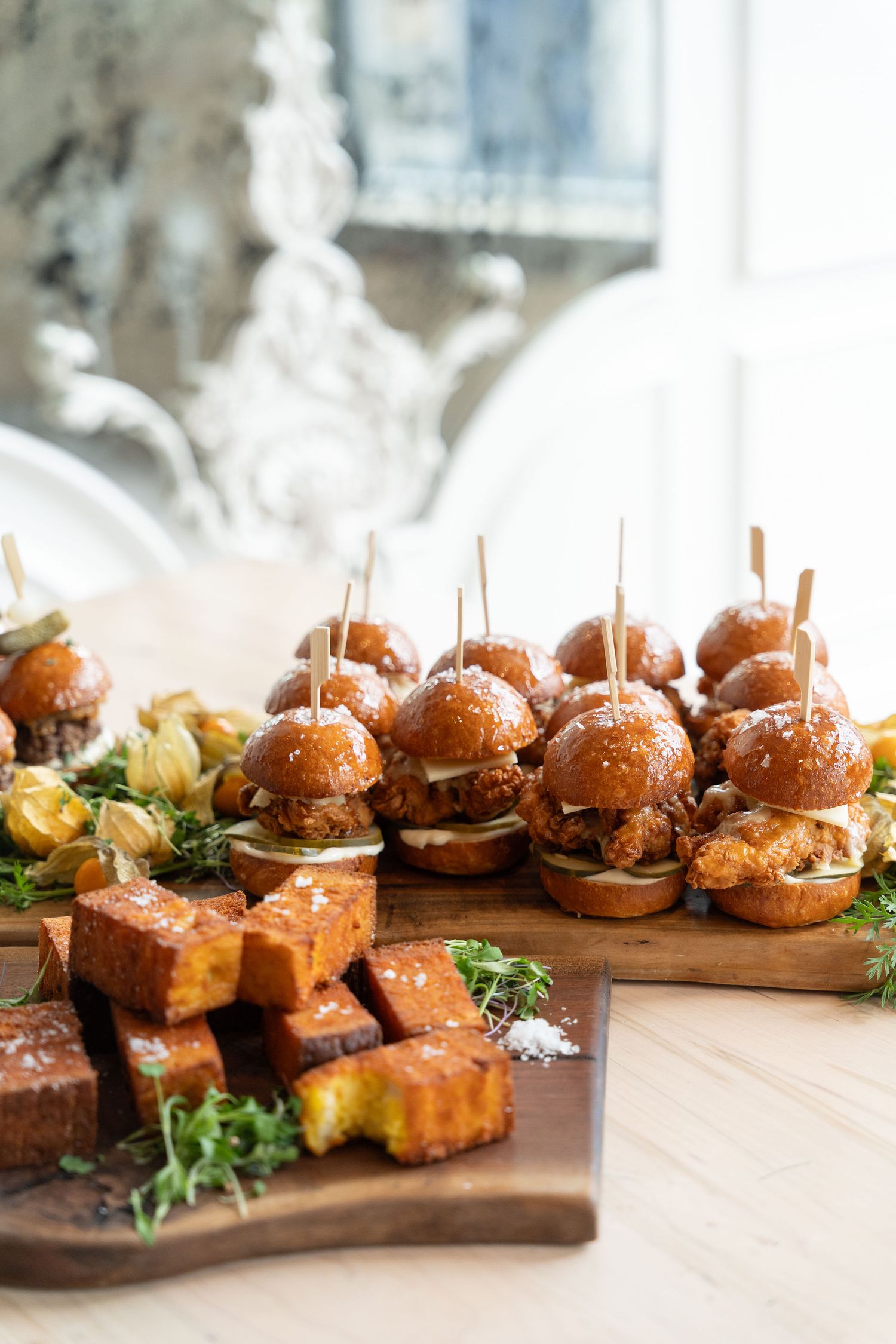 Artisanal sliders arranged on a rustic wooden serving board with fresh herbs and garnishes.