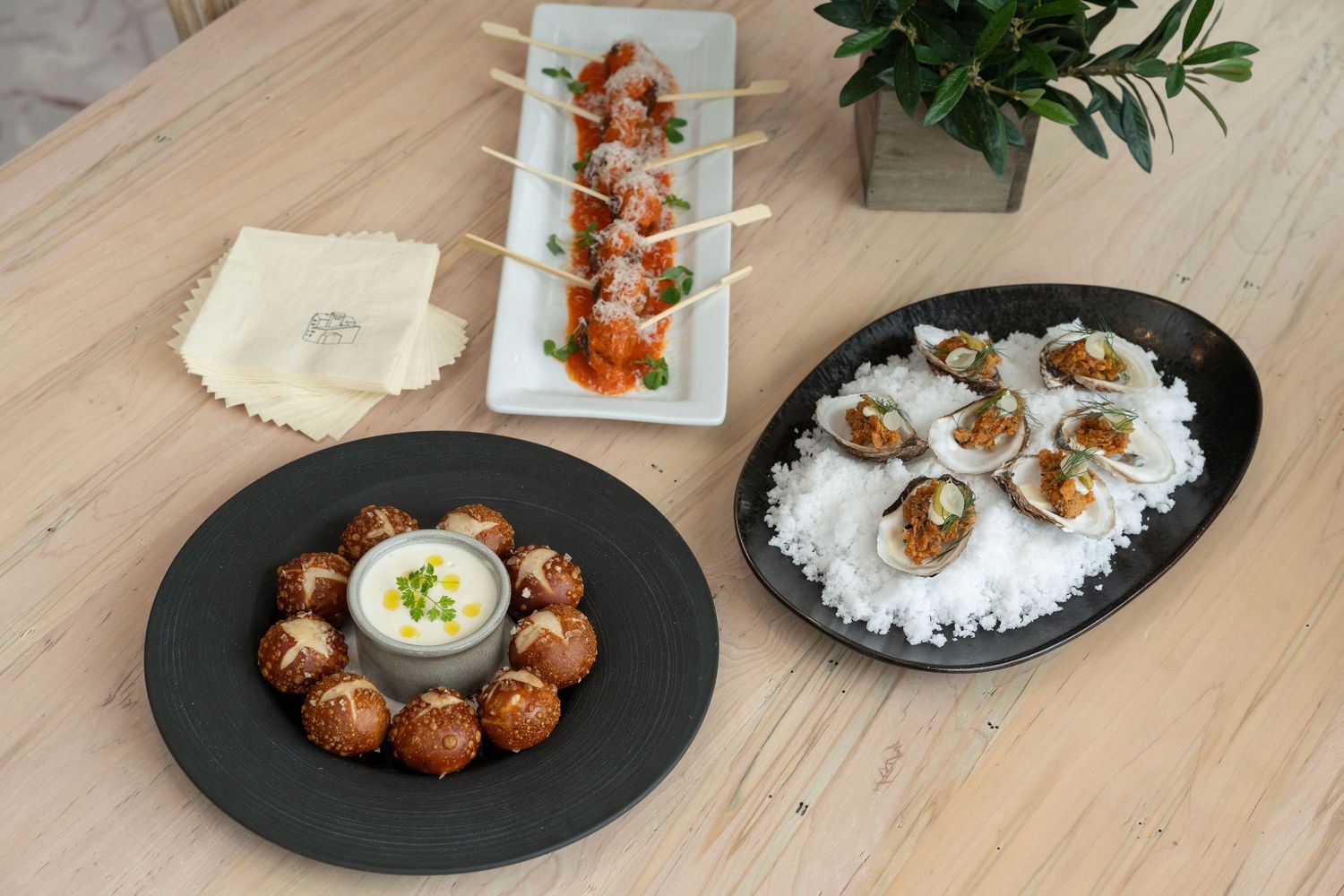 A collage of plated appetizers with rice, dipping sauce, and garnishes served on dark slate plates.
