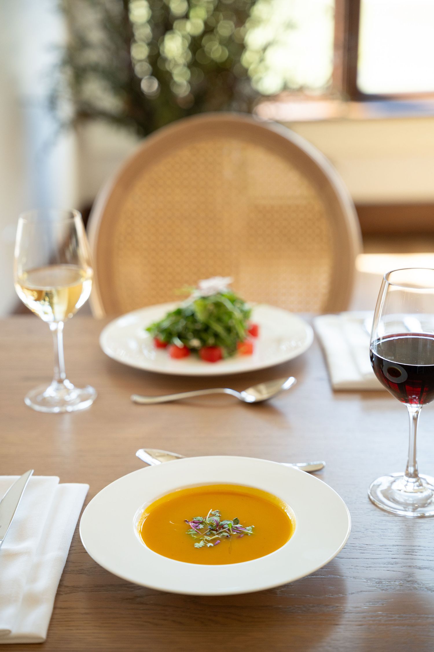 Elegant butternut squash soup served in white bowls on a formal dining table with wine glasses and place settings.