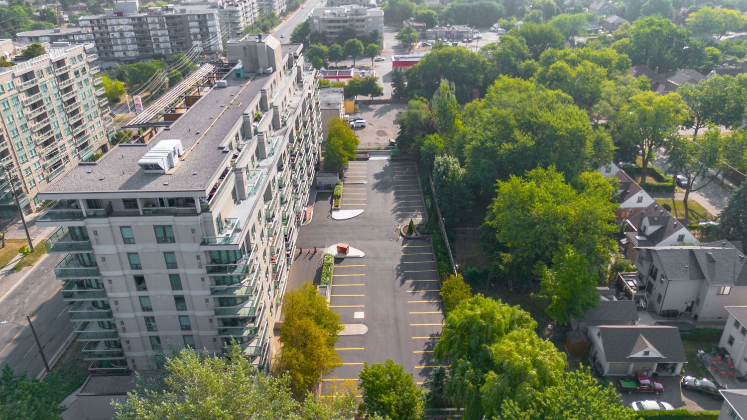 Aerial panoramic view of modern residential buildings and green trees in an urban neighborhood on a sunny day.