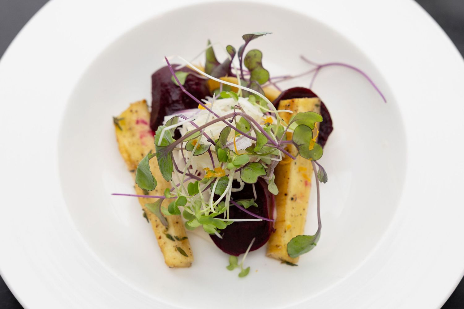 Elegant plated dishes featuring colorful microgreens and artistic culinary presentations on white plates.