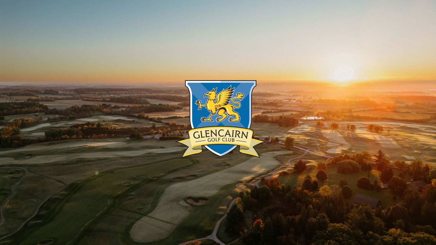 Panoramic aerial view of rolling farmland and fields at golden sunset with dramatic sky and long shadows.