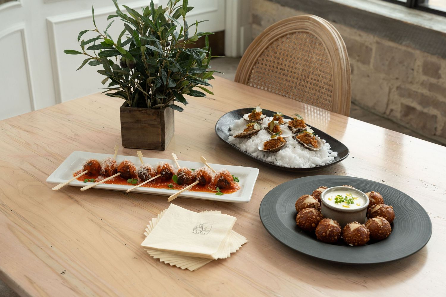 Modern restaurant interior with wooden tables and rattan chairs displaying various plated dishes.