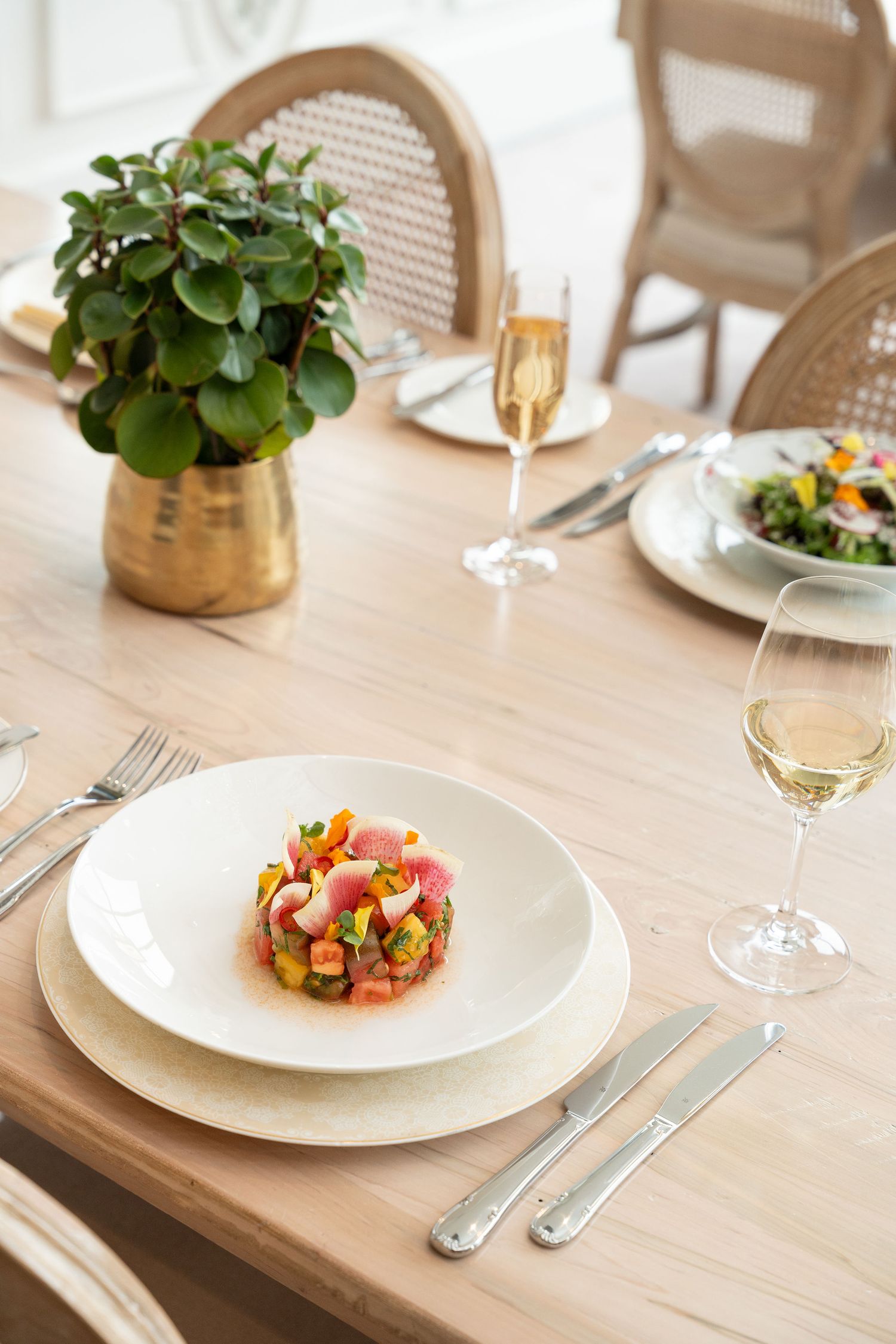 Fine dining plate with colorful tuna tartare garnished with microgreens and served with champagne.