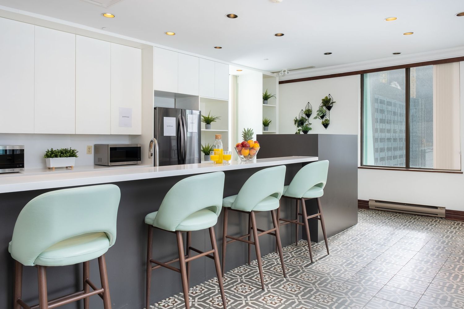 Modern dining area with mint green chairs and white tables arranged in rows against a bright office interior.